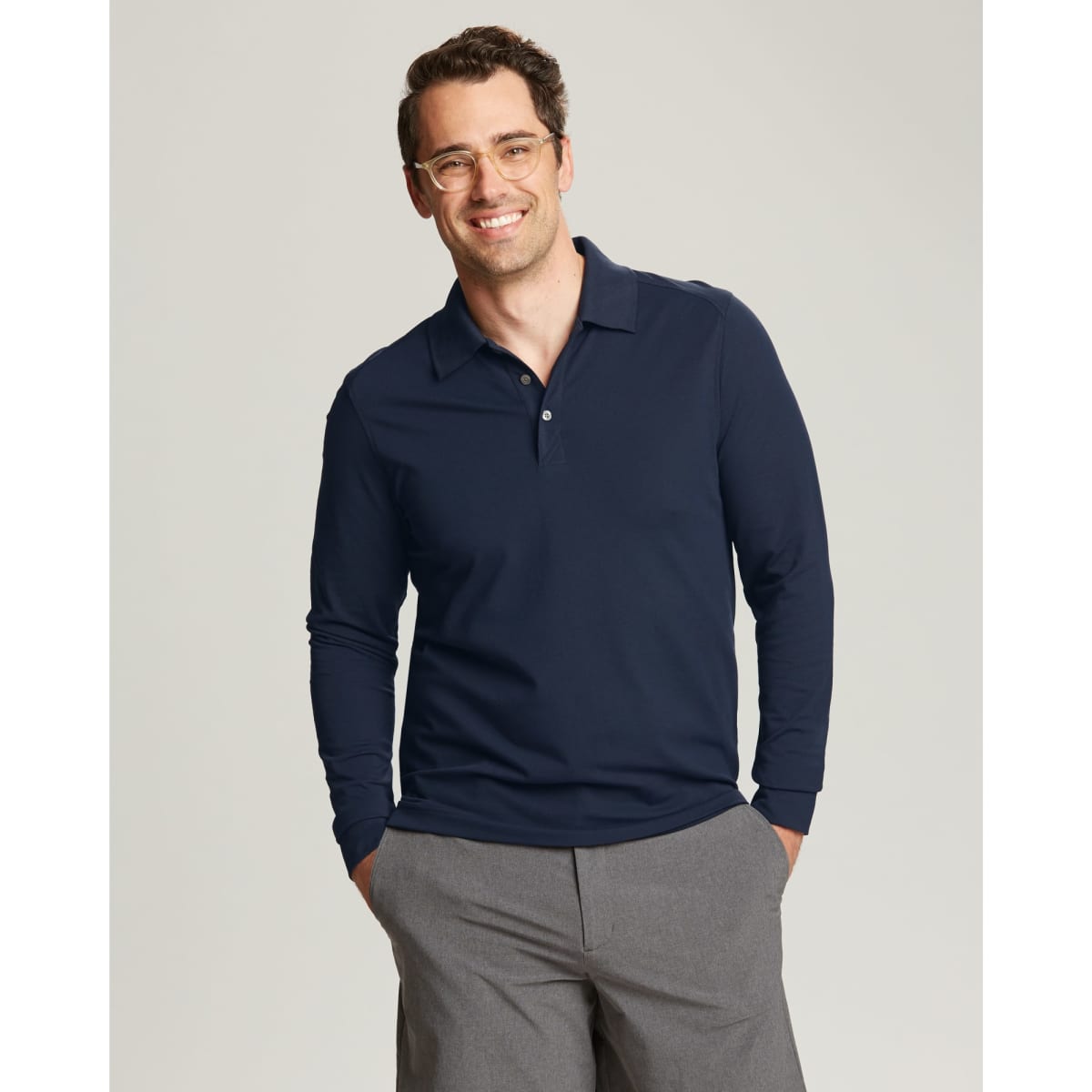 A man wearing a navy CB DryTec Long Sleeve Advantage Polo with a collar, featuring a logo.