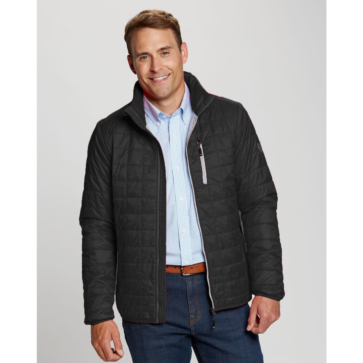 A man wearing a black weather-resistant jacket with a zippered front and a collar, featuring a small logo.