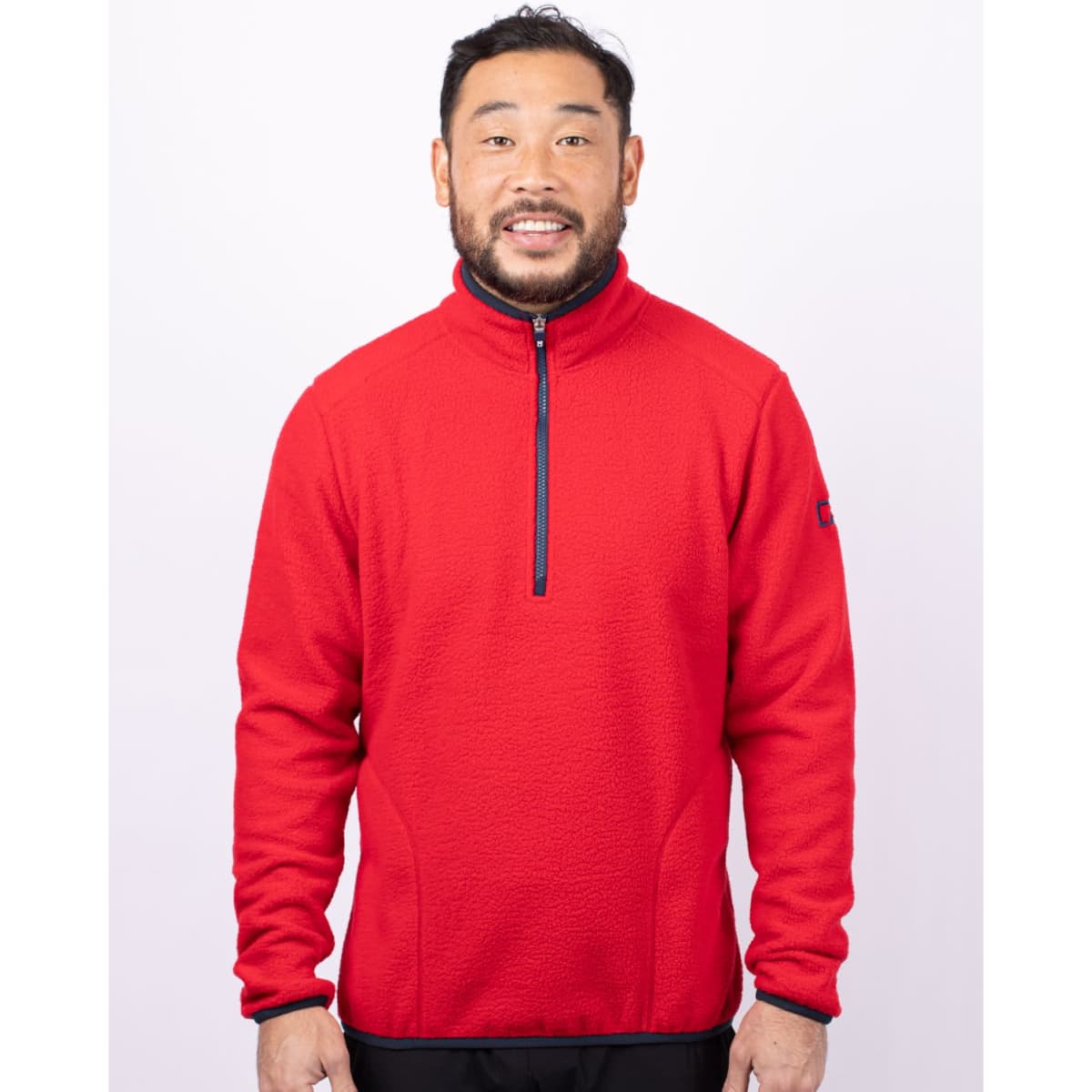 A man wearing a bright red half-zip fleece jacket with a zippered collar and a logo on the sleeve.