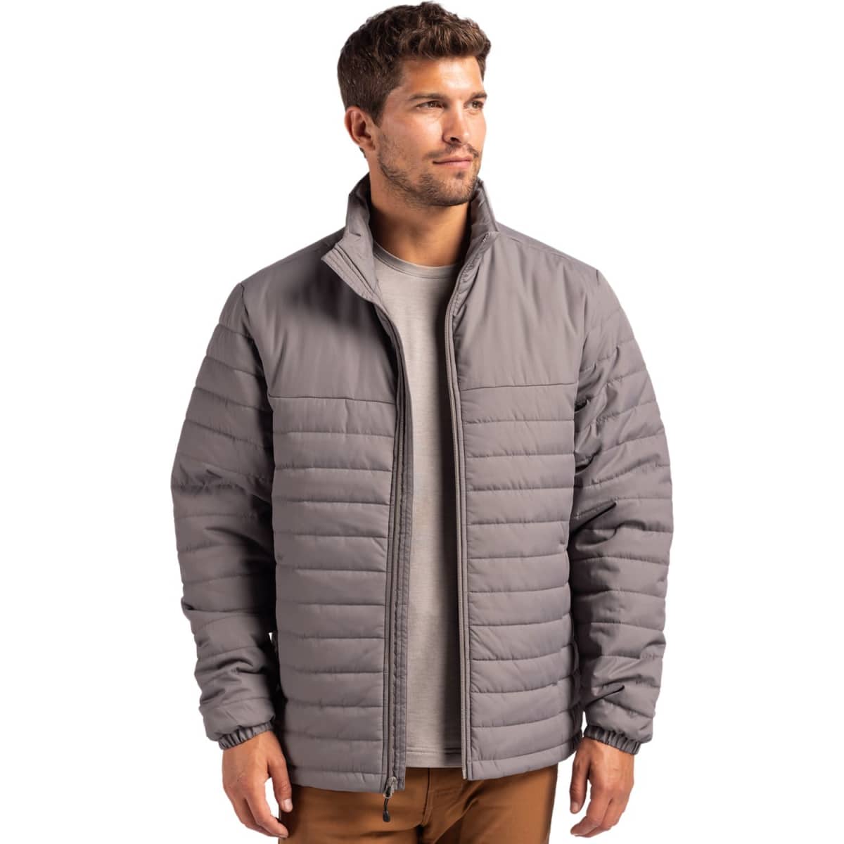 A man wearing a grey puffer jacket with a zip front and standing against a plain background.