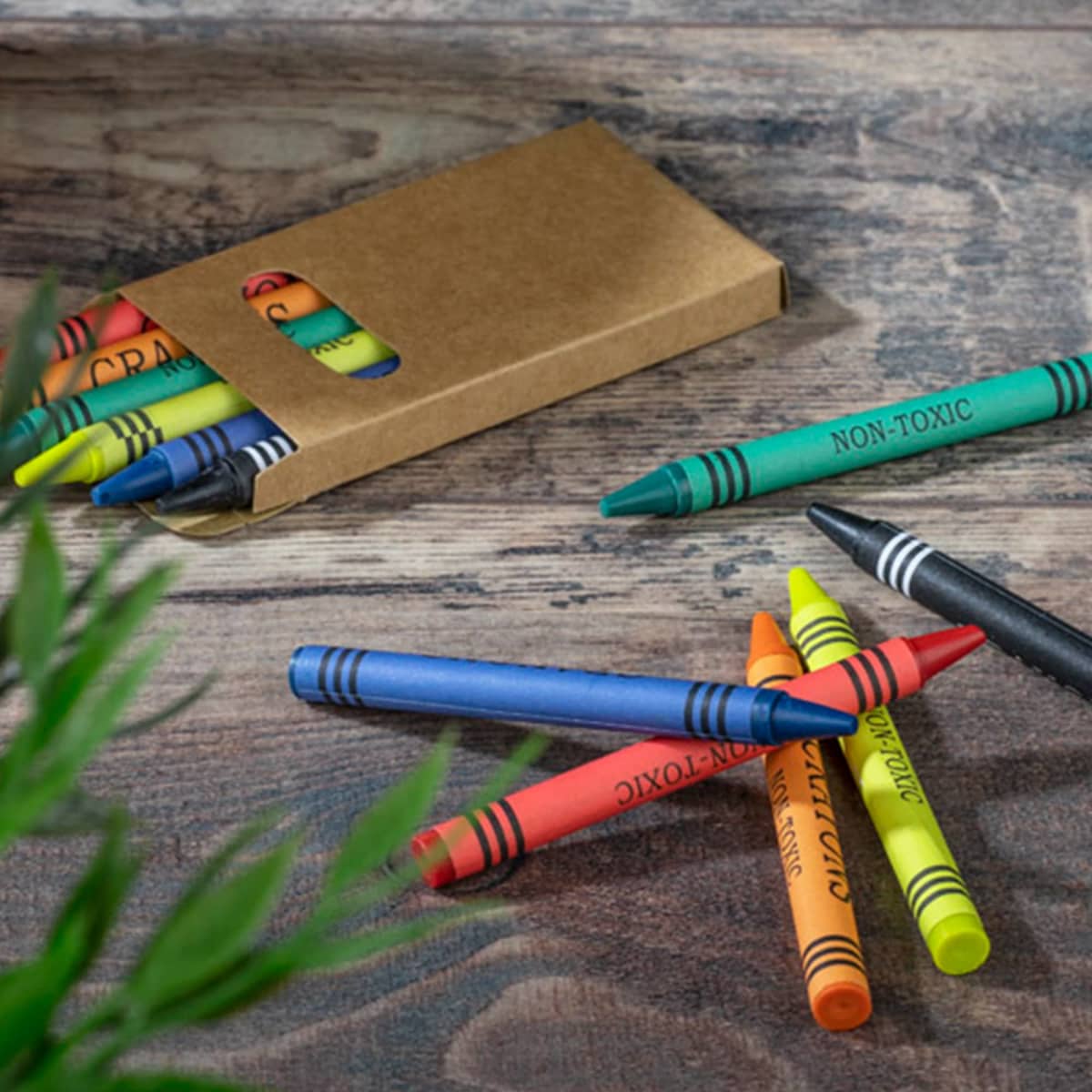 A crayon set featuring six non-toxic crayons in green, orange, blue, black, yellow, and red, packaged in a brown cardboard box.