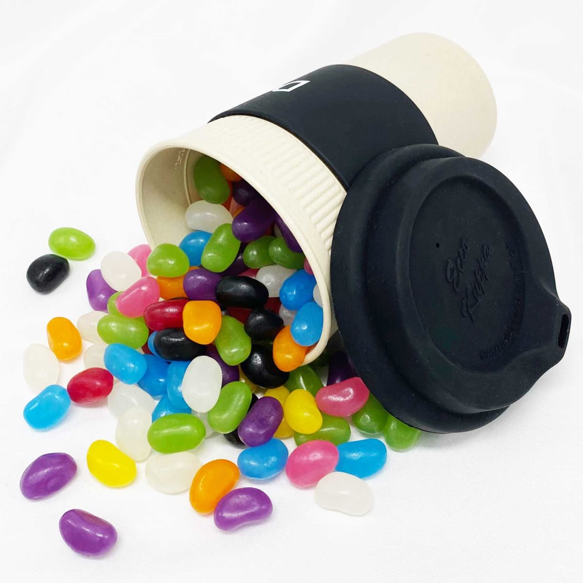 A bamboo cup in cream with a black lid, overflowing with colourful jelly beans in various shades.