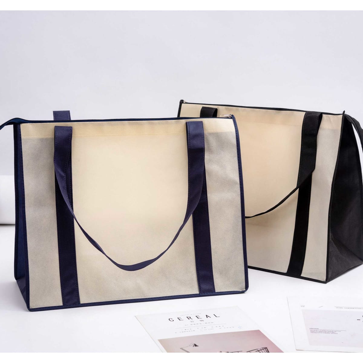 A large non-woven zipped shopping bag in beige and navy, featuring handles and an interior space.