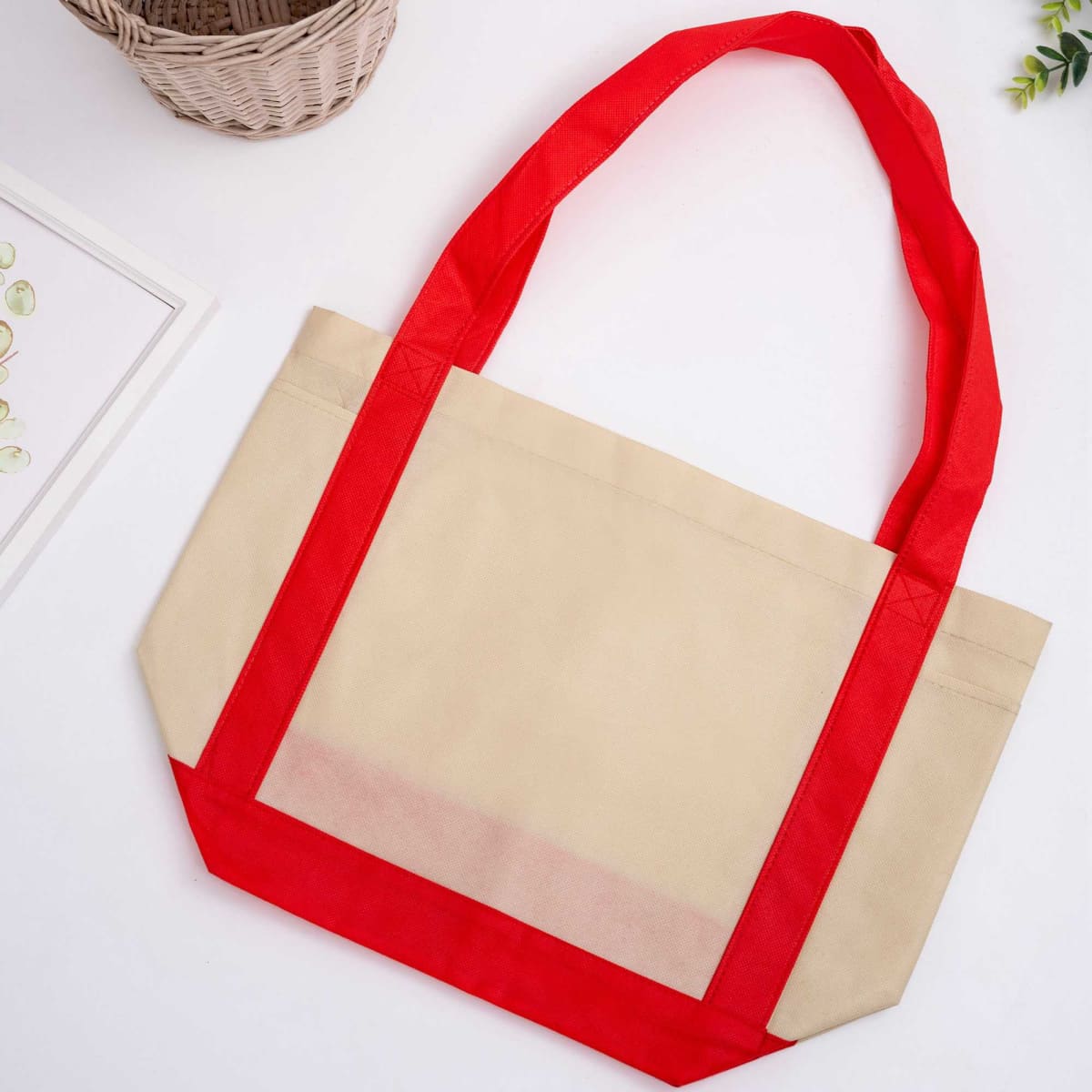 A non-woven reusable grocery bag in beige with bright red handles and accents, featuring a logo.
