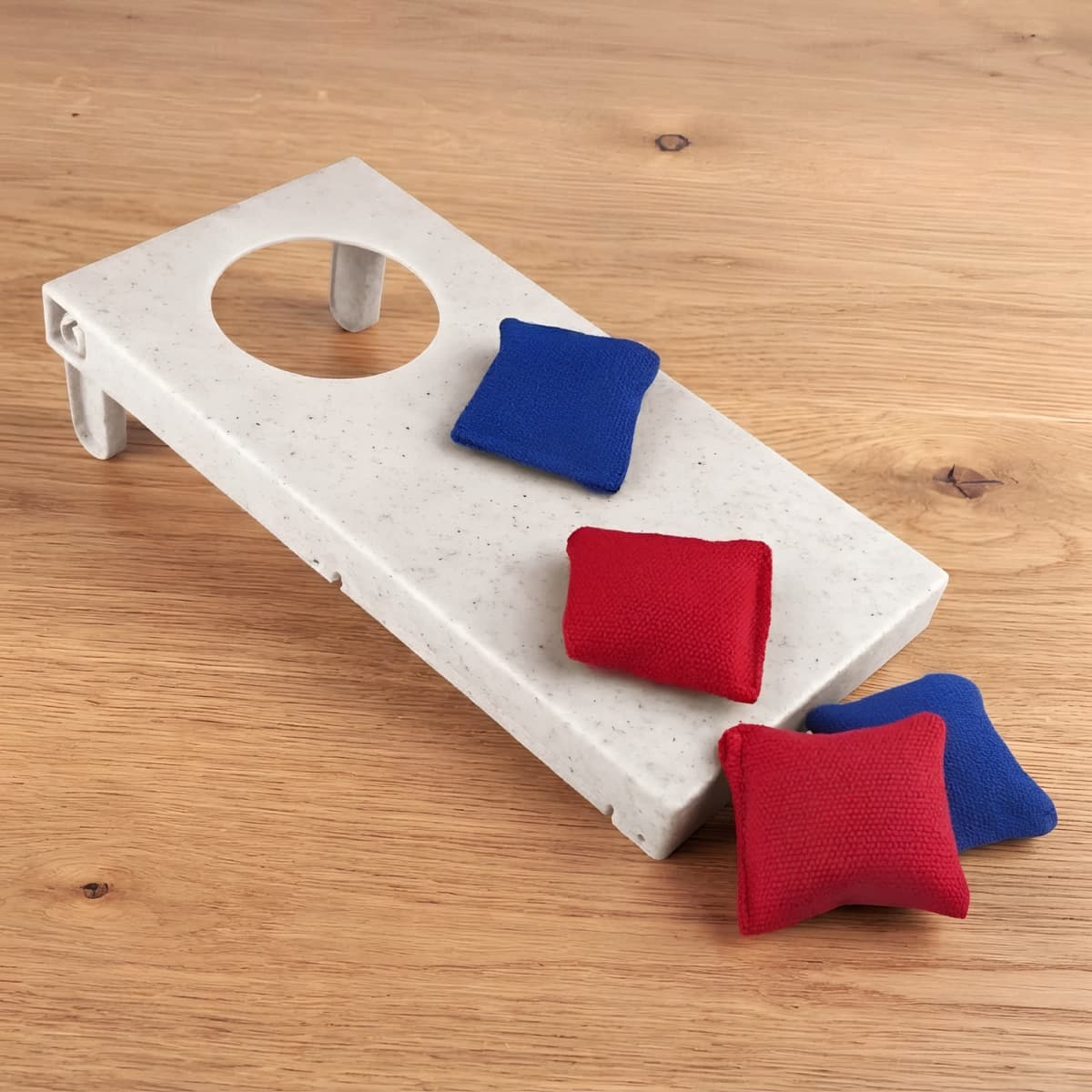 A cornhole board made of wheat straw in a light colour, accompanied by four small, red and blue bean bags.