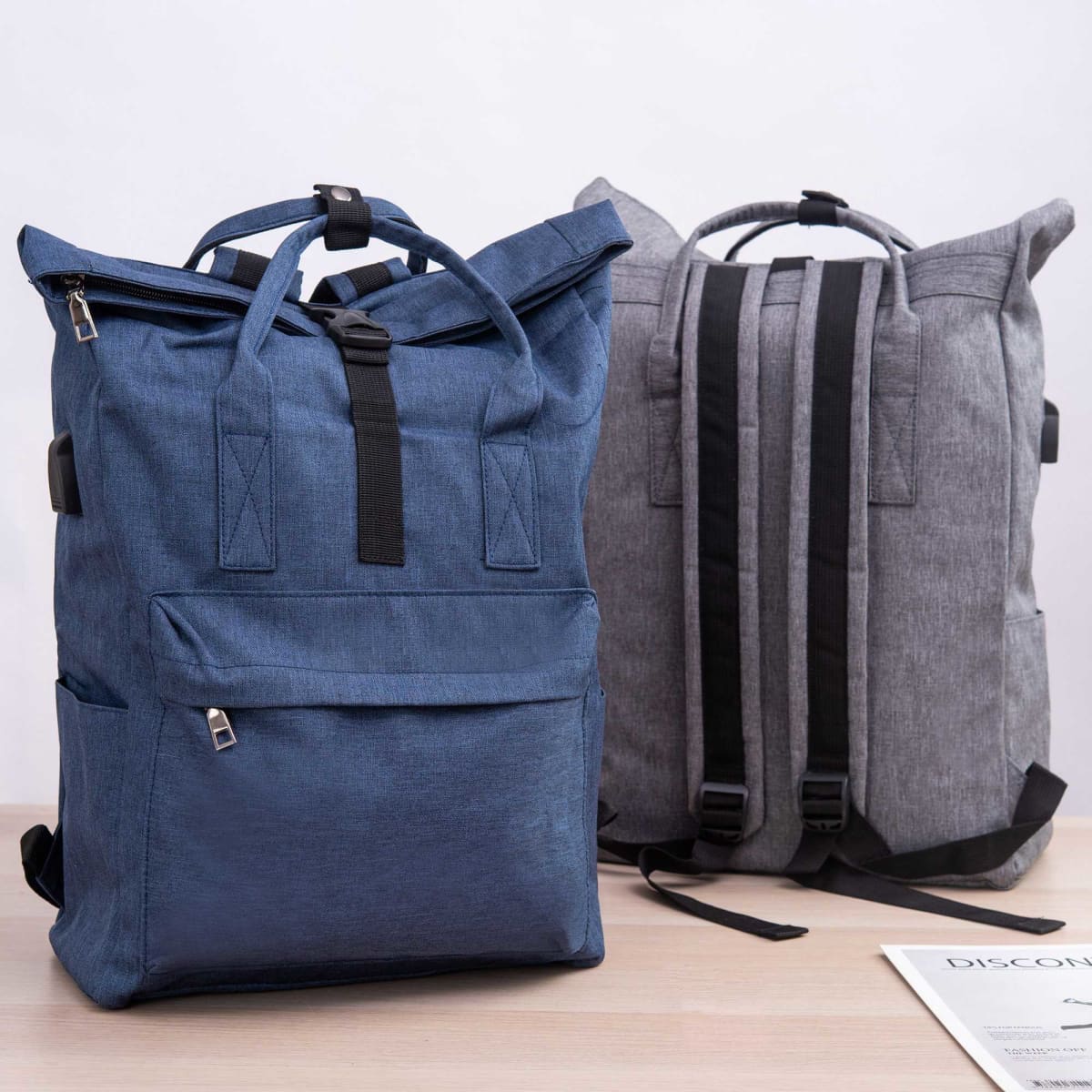 A blue and grey laptop backpack with adjustable straps and front pockets, featuring a logo on the front.