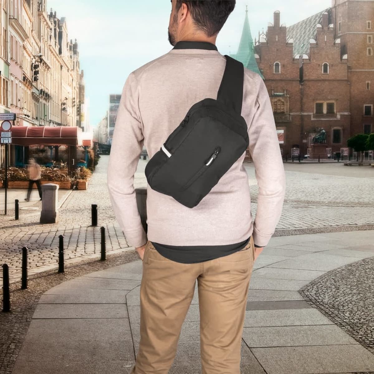 A black single strap backpack made from recycled polyester, worn by a person in a city setting.