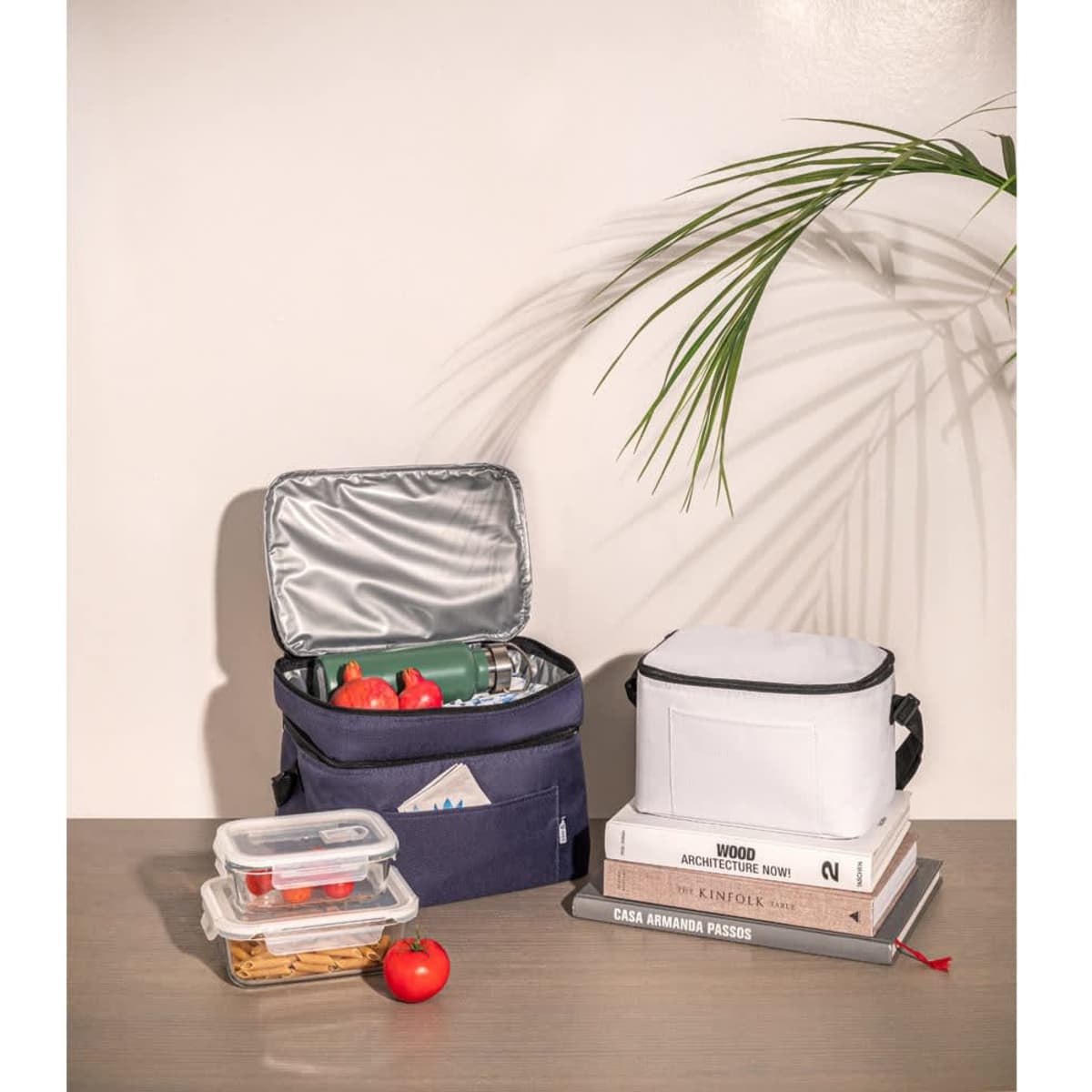 A navy thermal bag made from recycled polyester, containing food containers, a drink bottle, and tomatoes.