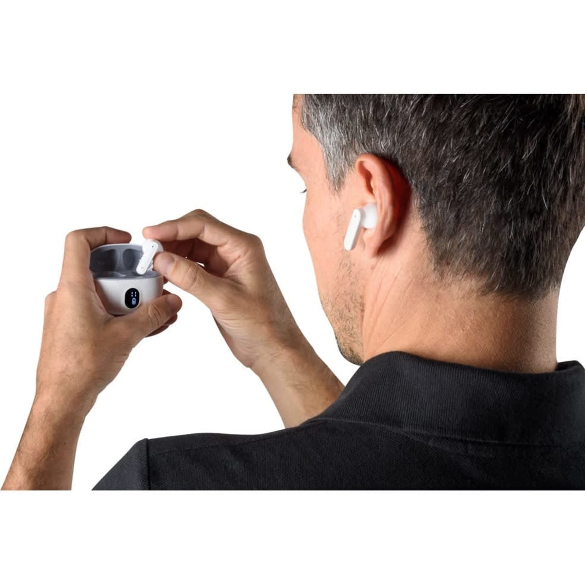 Wireless earphones in white being held by a person, with a carrying case visible in their other hand.