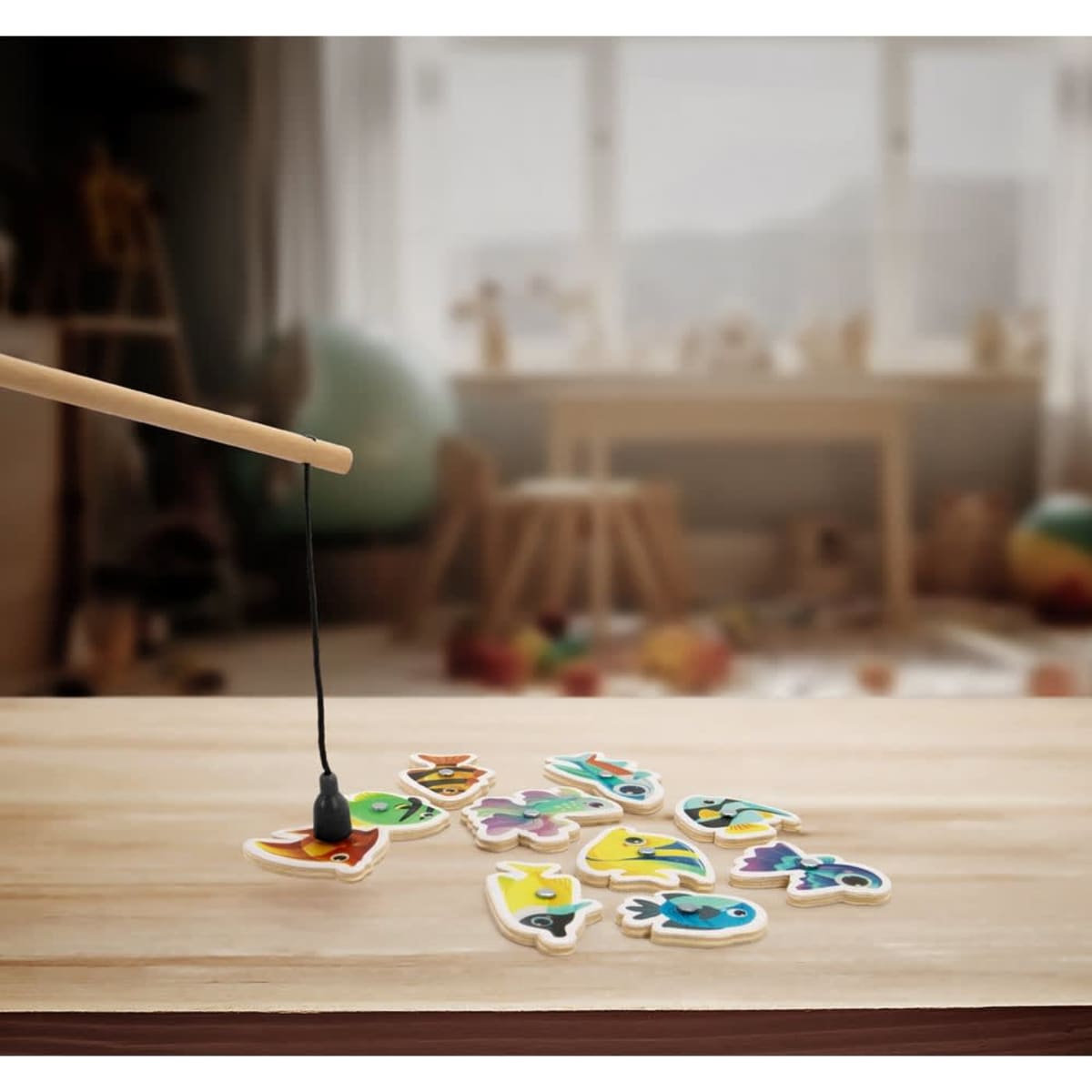 A wooden fishing game with ten colourful fish pieces scattered on a table, accompanied by a fishing rod.