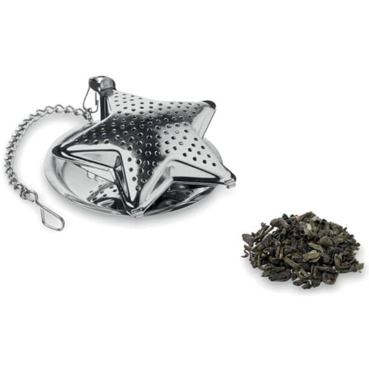 A star-shaped tea infuser in shiny silver with a chain, next to a pile of loose green tea leaves.