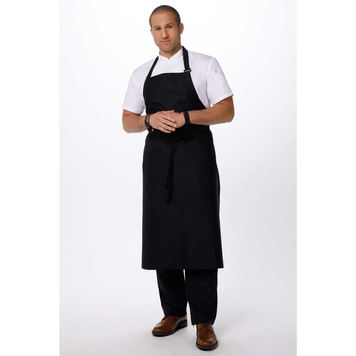 A black large bib apron worn by a model in a white shirt and black pants, featuring a logo on the apron.