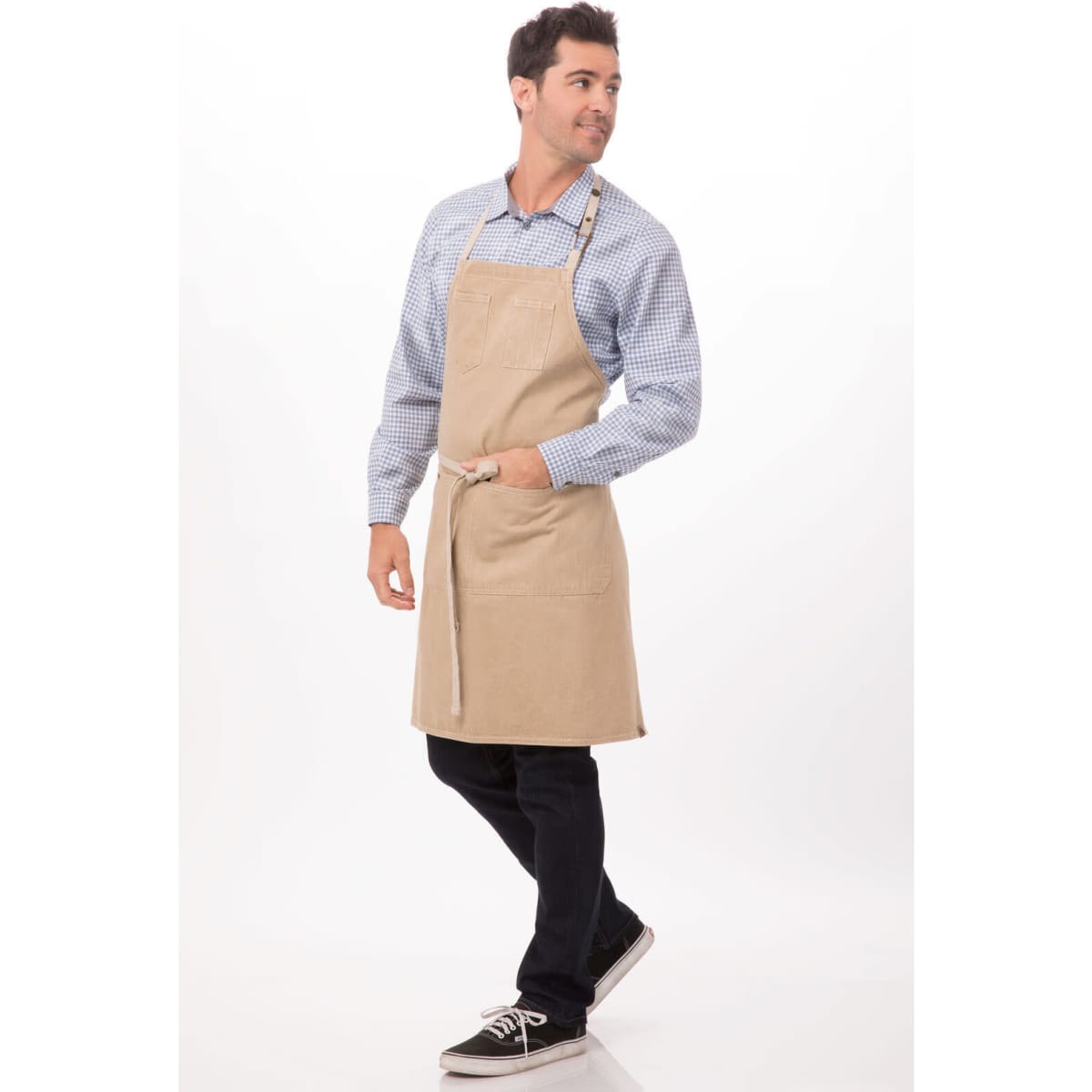 A beige bib apron worn by a man, featuring a pocket and adjustable straps, against a light background.
