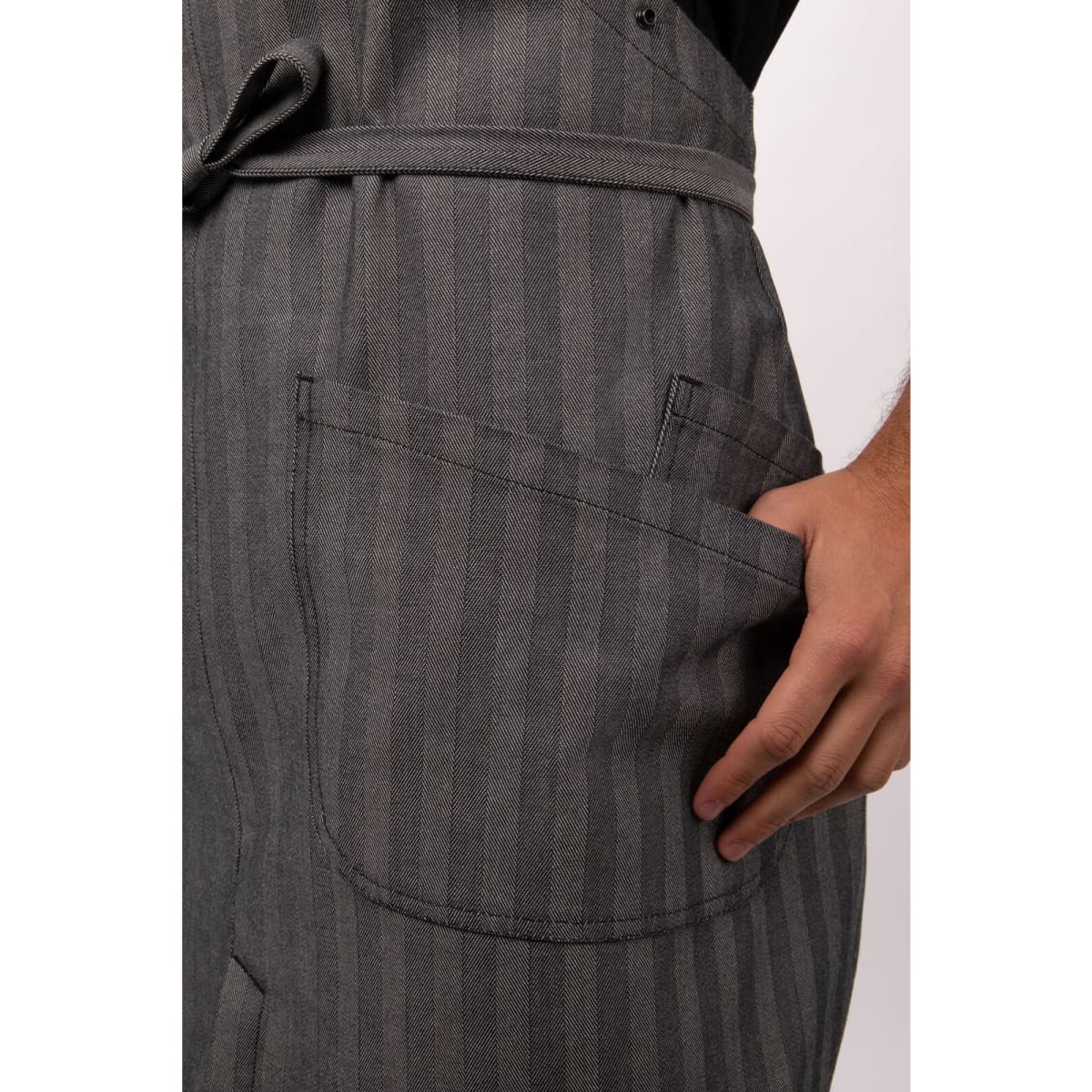 A grey striped apron with a pocket, featuring a hand placed inside the pocket.