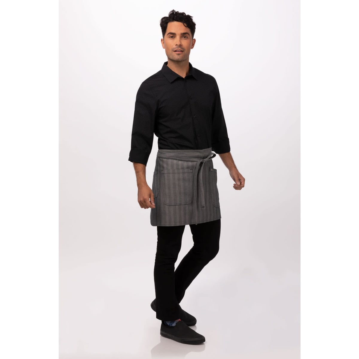 A man wearing a grey striped bistro apron over a black shirt and pants, featuring a logo on the apron.
