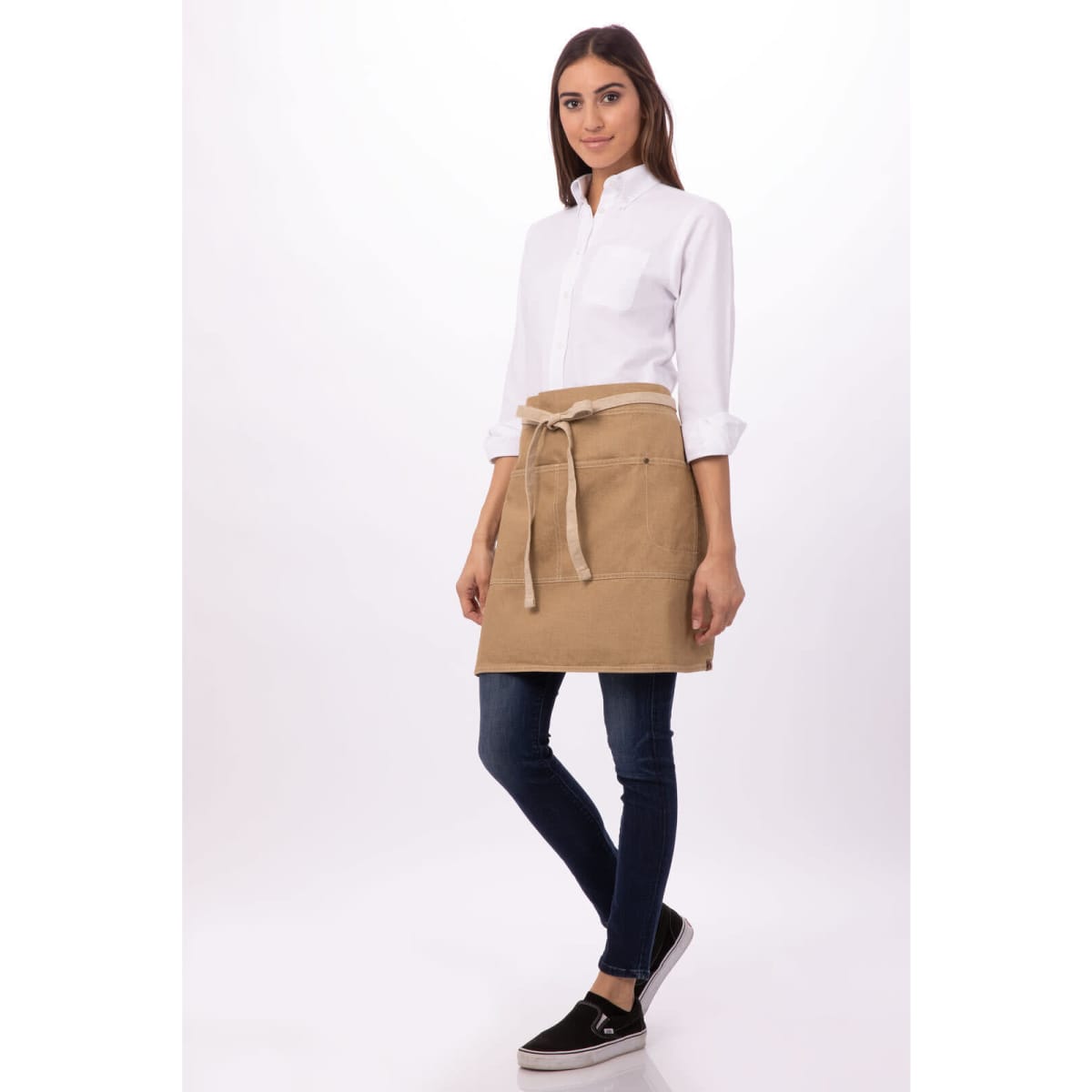 A bistro apron in a tan colour, tied at the waist, worn over a white shirt and dark jeans. A logo is visible.