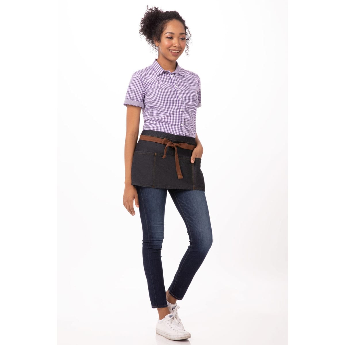 A black waist apron with a brown tie, worn over a checked shirt and jeans by a model.