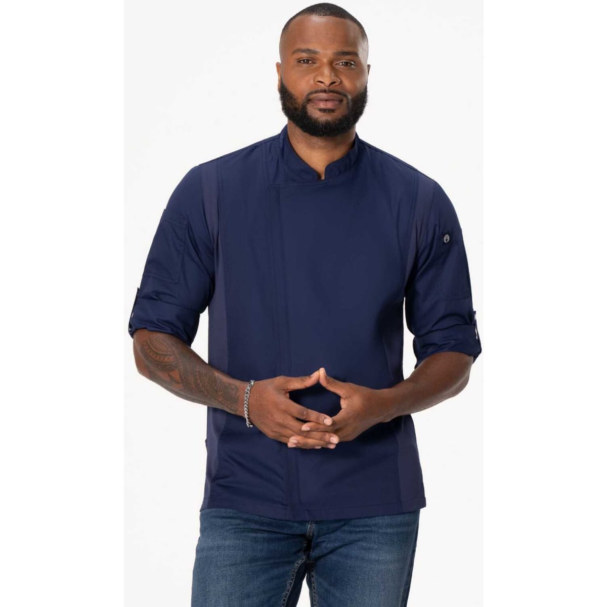 A men's chef jacket in navy blue, featuring a logo and three-quarter sleeves, modelled by a man with a beard.