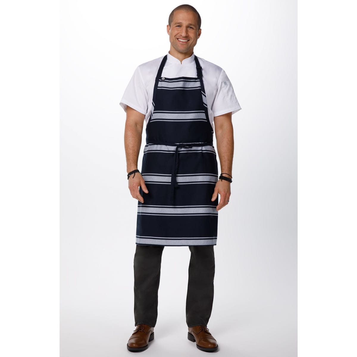 A man wearing a navy butcher stripe bib apron over a white shirt and dark trousers, with a logo on the apron.