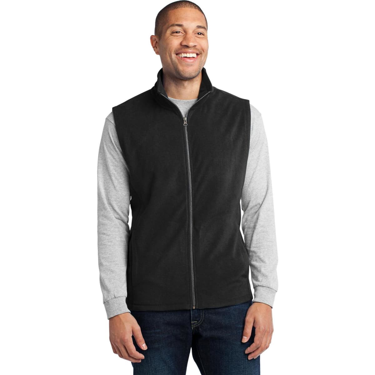 A man is wearing a black microfleece vest over a grey long-sleeve shirt, smiling. The vest has a logo.