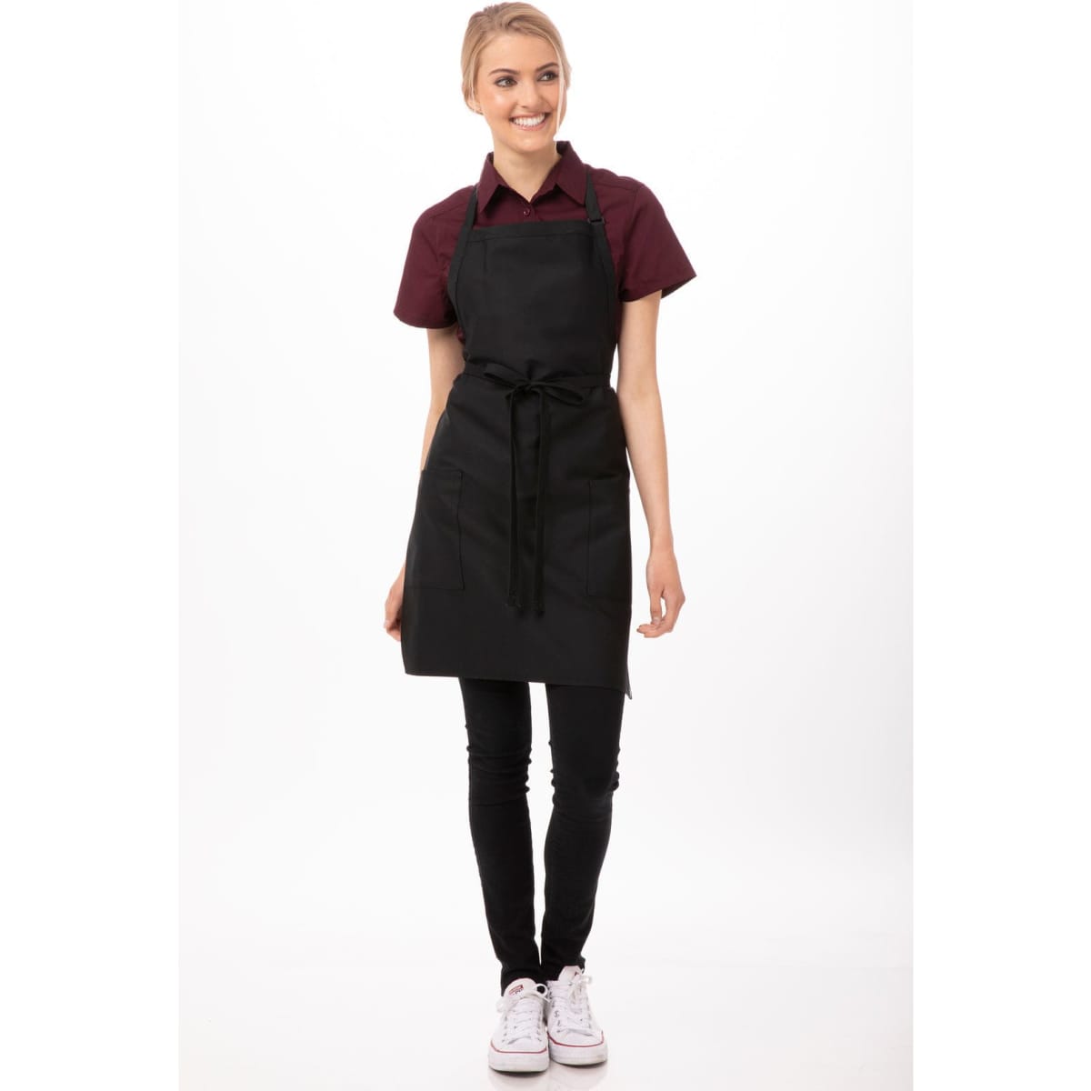 A black bib apron with two patch pockets worn over a dark shirt and black pants, featuring a branding logo.