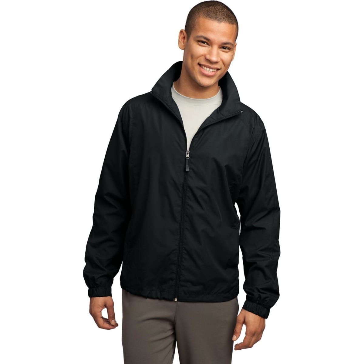 A man wearing a black full-zip wind jacket, smiling, with a stand-up collar and elastic cuffs. The jacket has a logo.