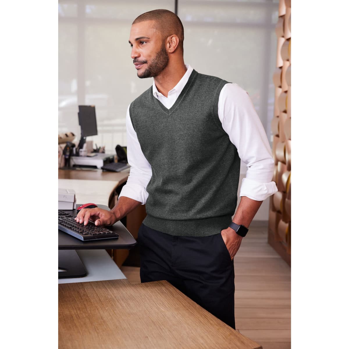 A grey sweater vest worn over a white shirt, featuring a classic V-neck design and a branding logo.
