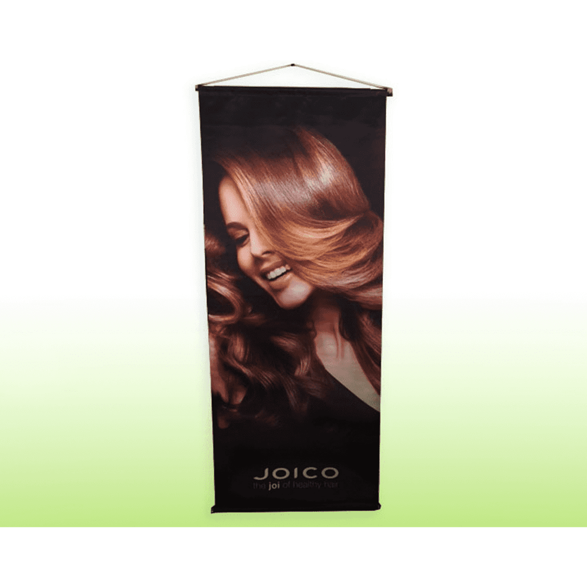 A hanging vinyl banner featuring a close-up of a woman with flowing, wavy hair and a dark background. It has a logo at the bottom.