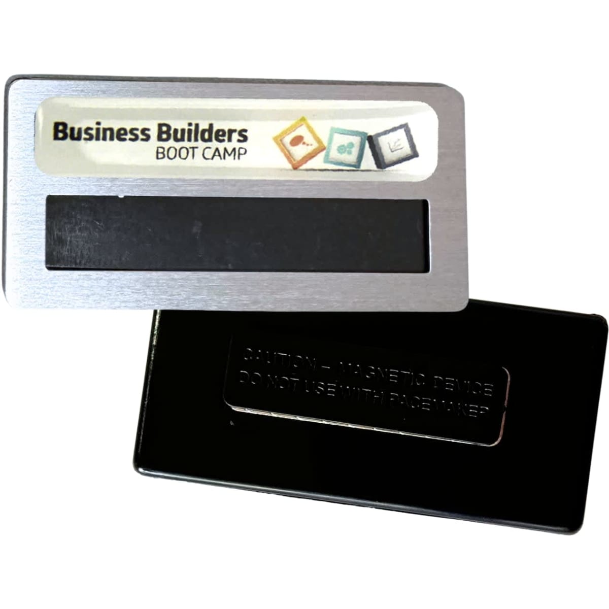 A silver DIY staff badge featuring an epoxy label magnet with a black backing. Includes a logo or branding.