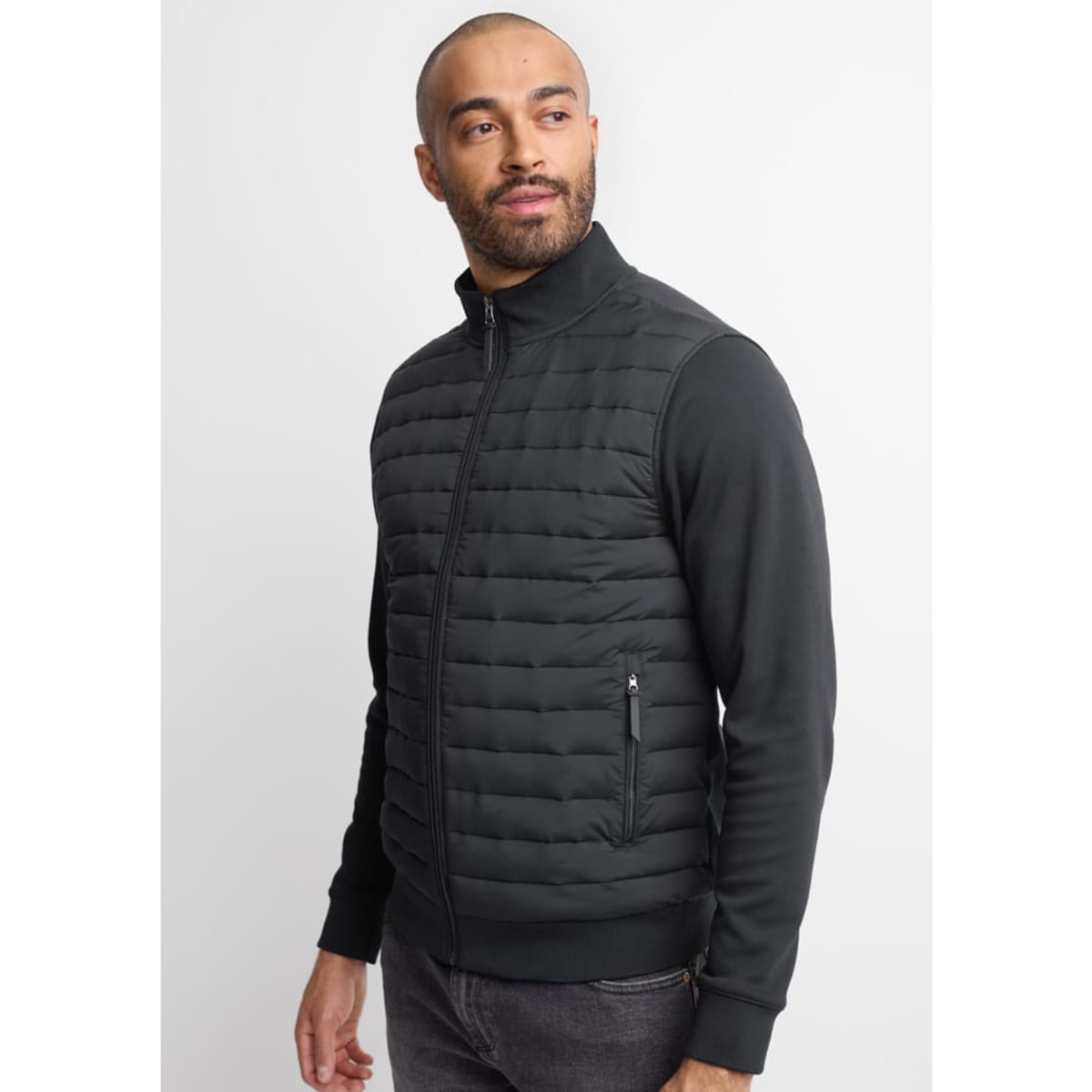 A men's tailored jacket in black, featuring quilted detailing and a zippered pocket on the side.
