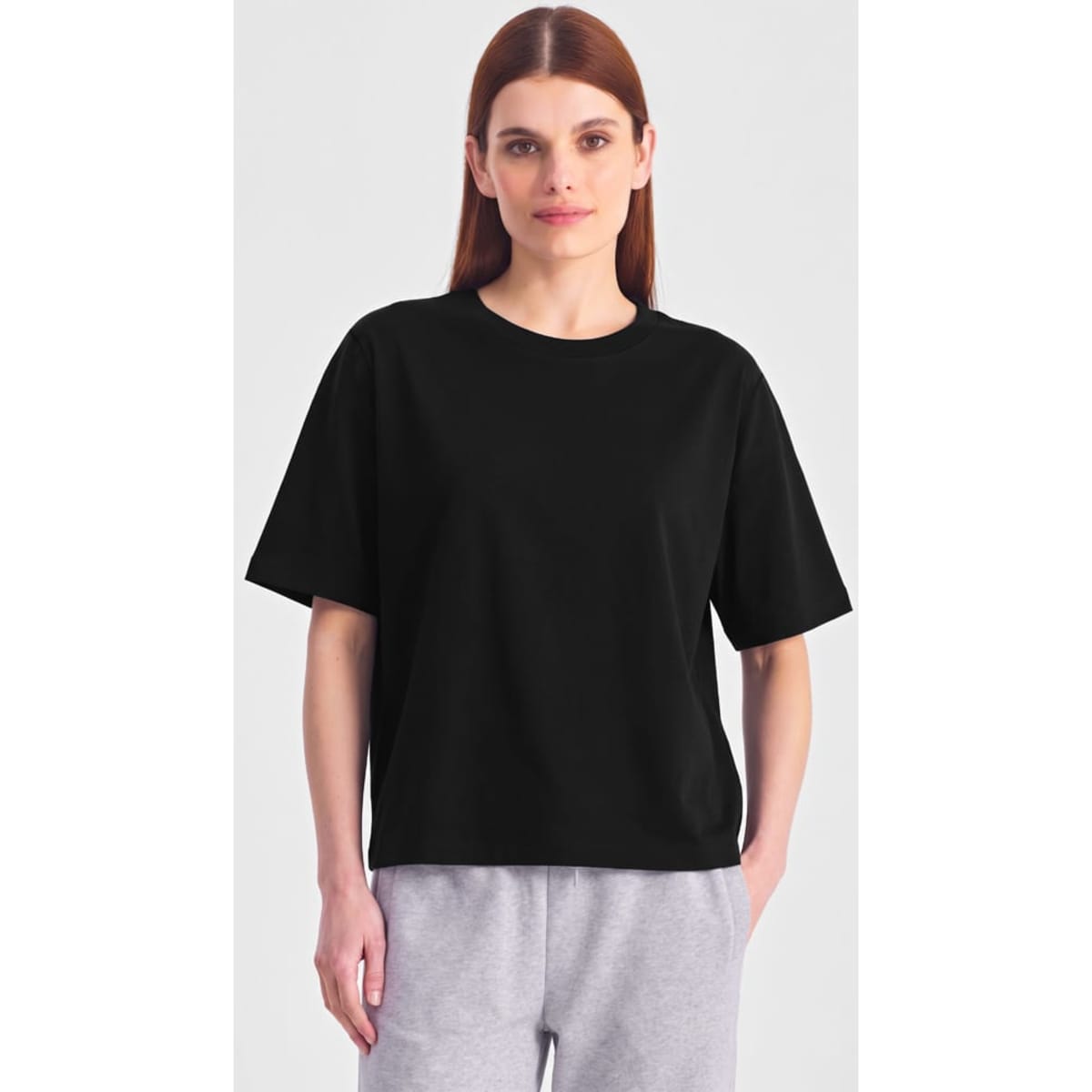 A black box tee in a relaxed fit, featuring short sleeves. The model wears it with grey bottoms.