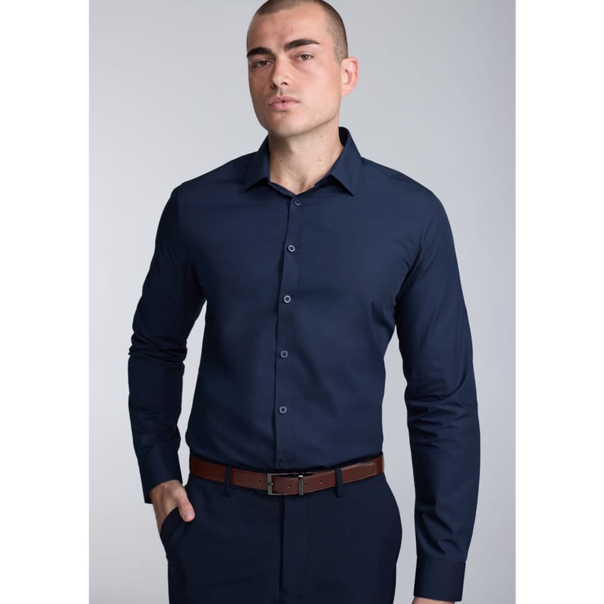 A fitted long sleeve shirt in navy blue, featuring a button-up front and a sleek collar, worn by a model.