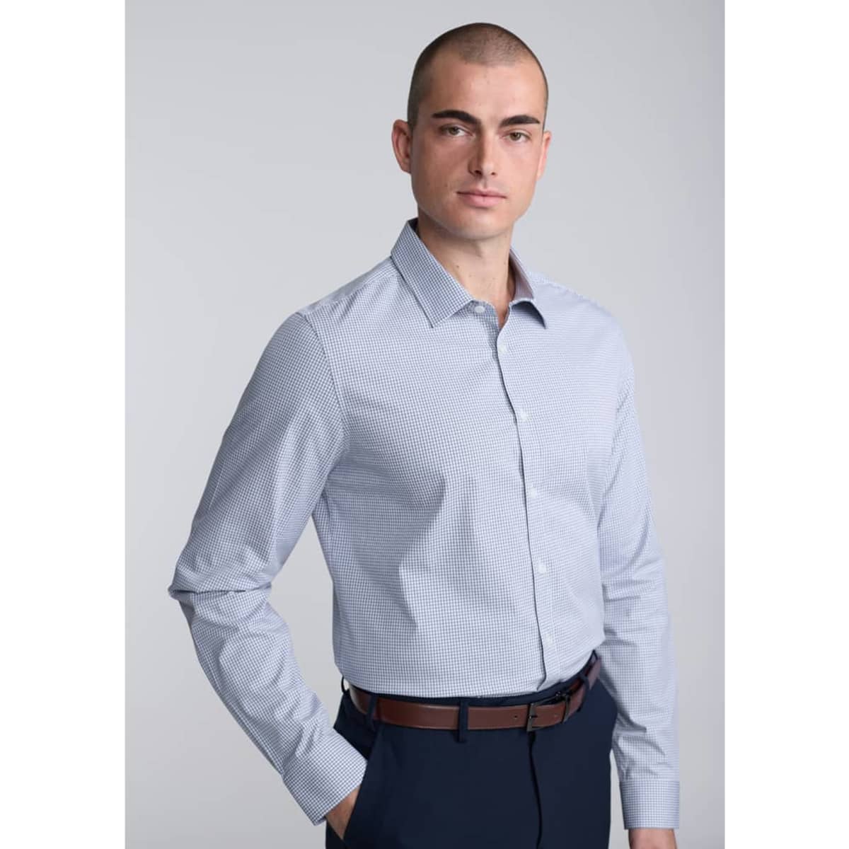 A slim fit long sleeve shirt in a light blue check pattern, worn by a model with a shaved head.