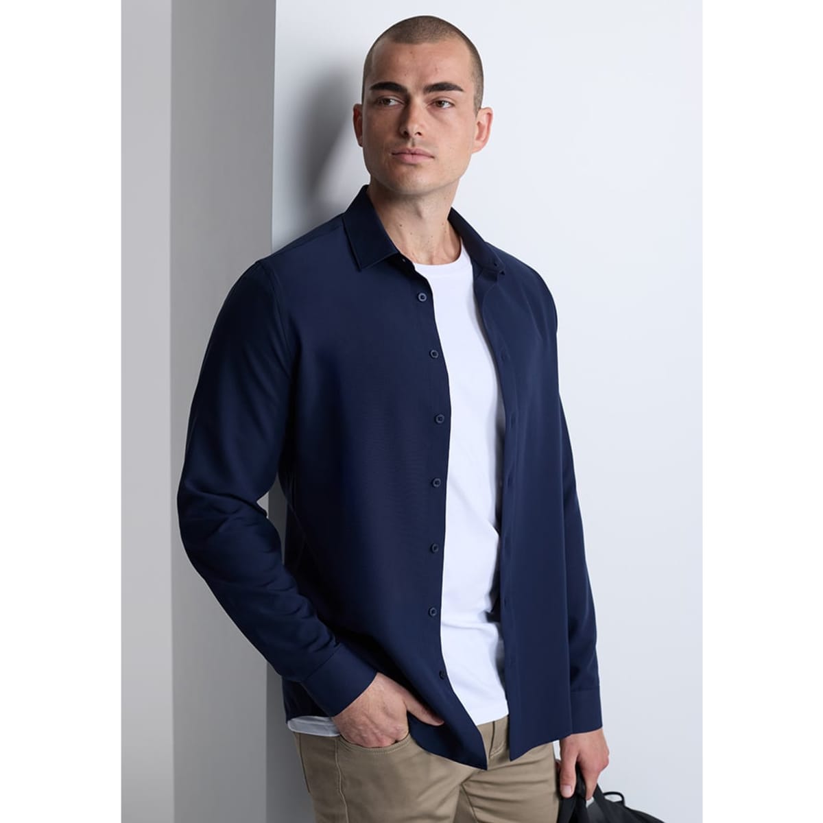 A navy long sleeve shirt with a button-up front, worn over a white t-shirt, paired with beige trousers.