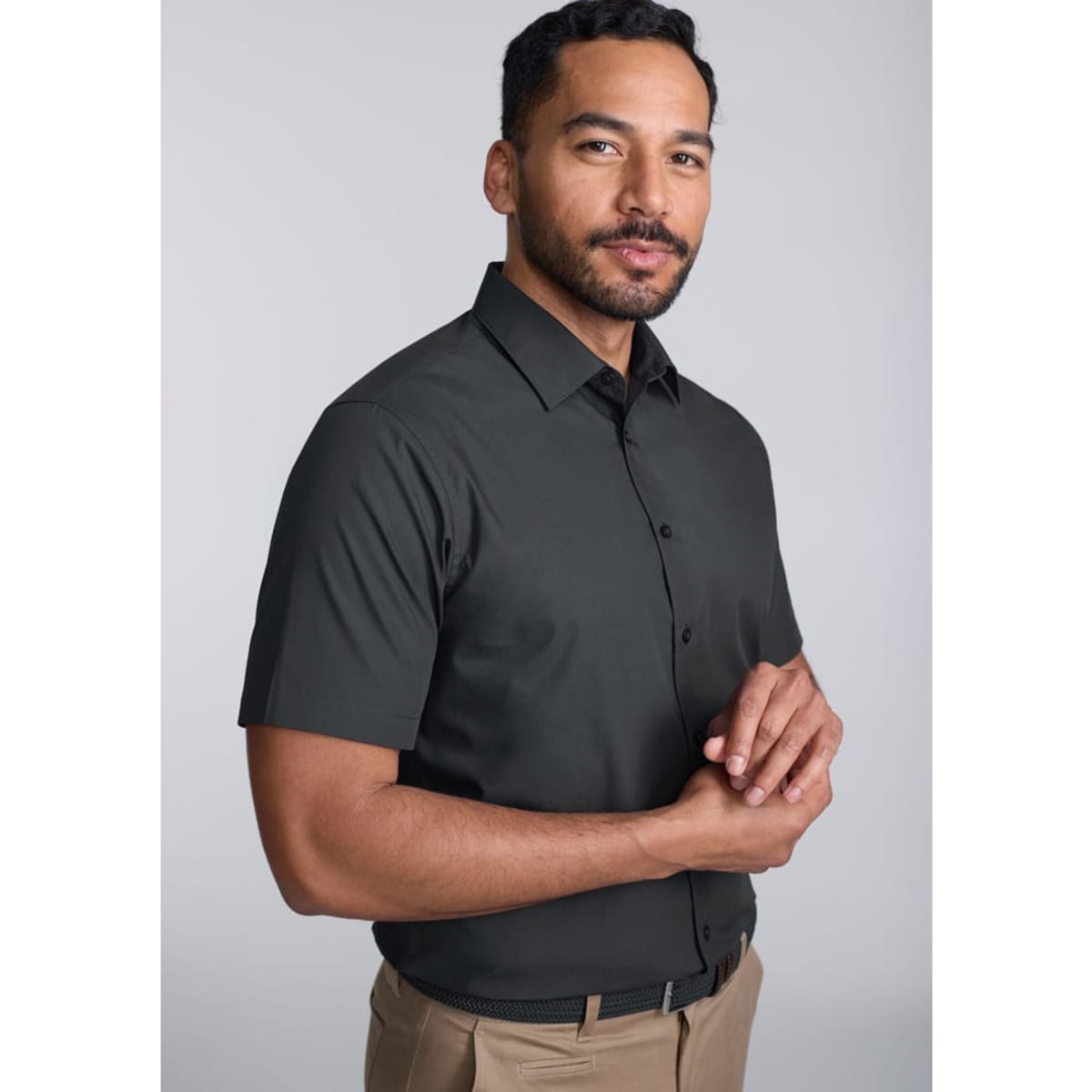 A classic fit short sleeve shirt in dark grey, featuring a button-up design. The model stands with a neutral expression.