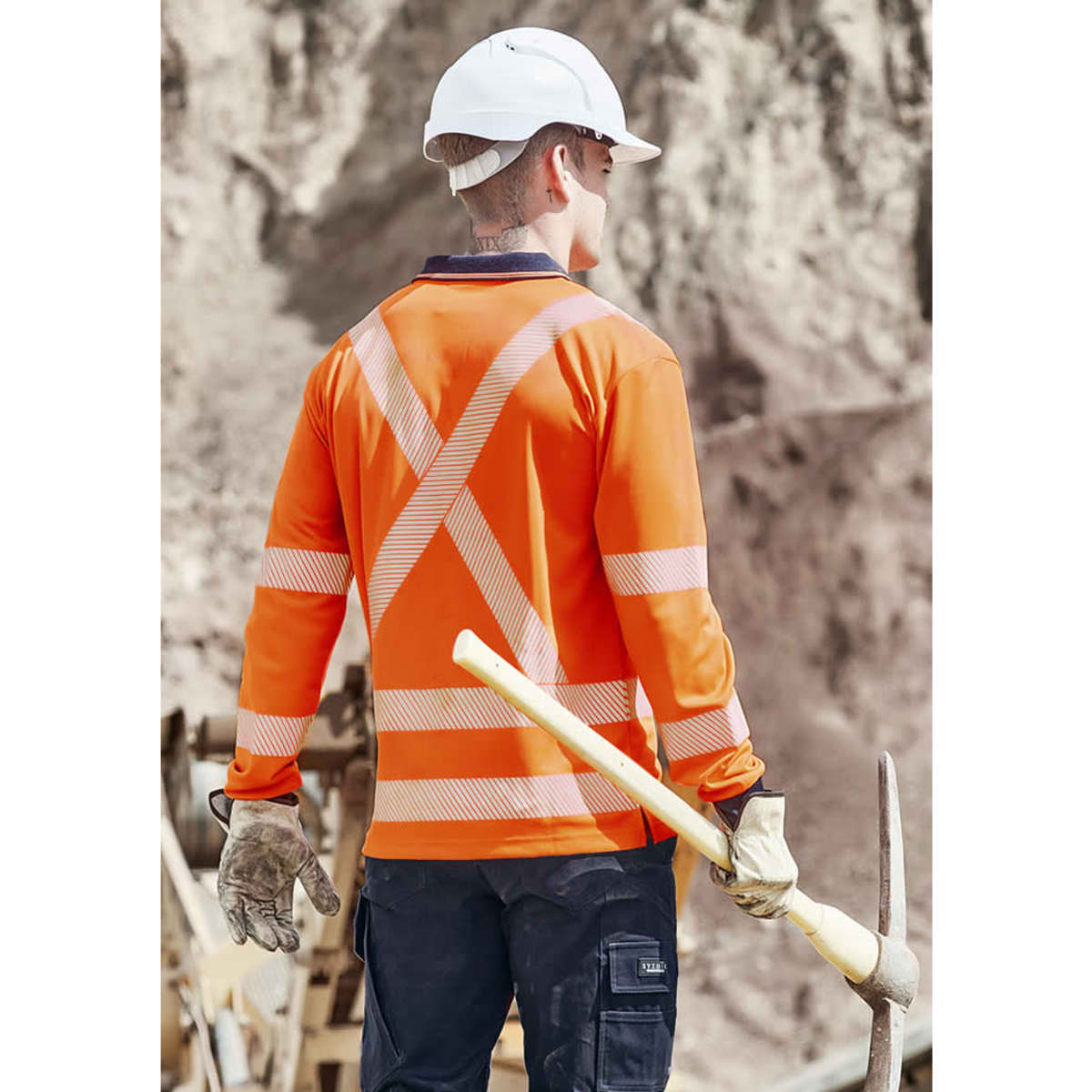 A long sleeve polo shirt in hi-vis orange with reflective stripes, worn by a worker on a construction site.