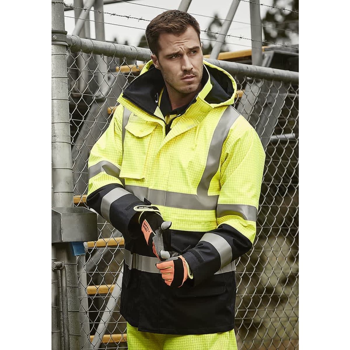 A man's high-visibility waterproof jacket in yellow and black with reflective strips, worn with gloves.