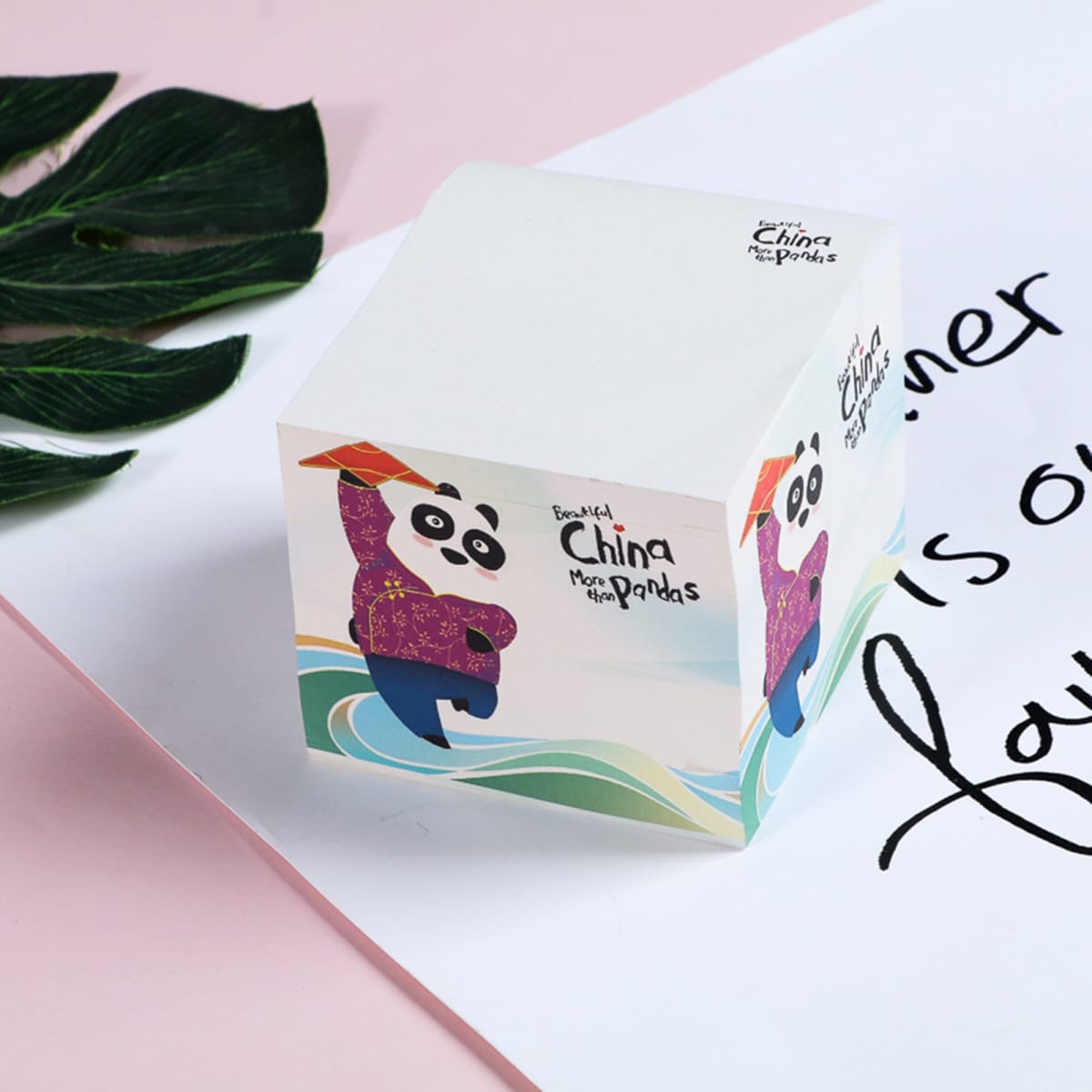 A square cube of sticky notes featuring a panda design, predominantly in white with colourful accents.