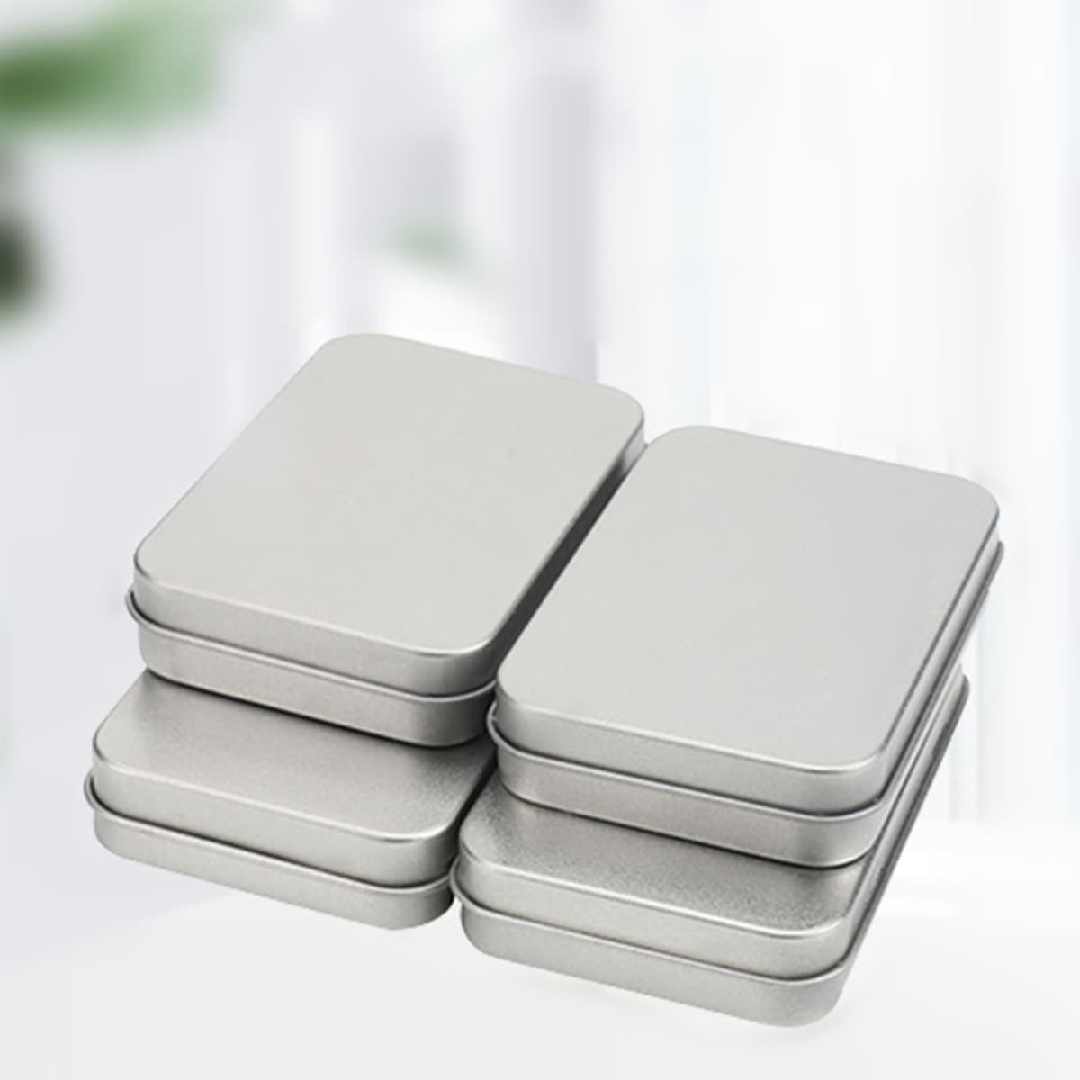A set of silver tinplate boxes stacked together, featuring a smooth finish and rectangular shape.