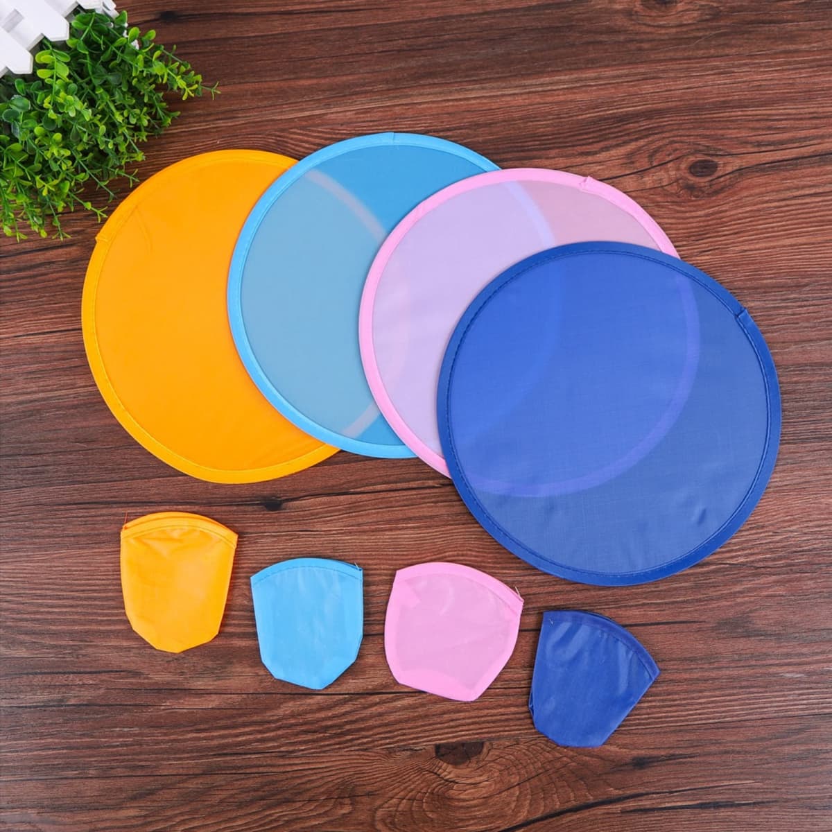 Four colourful folding flying discs in yellow, blue, pink, and purple, along with smaller pouches for storage.