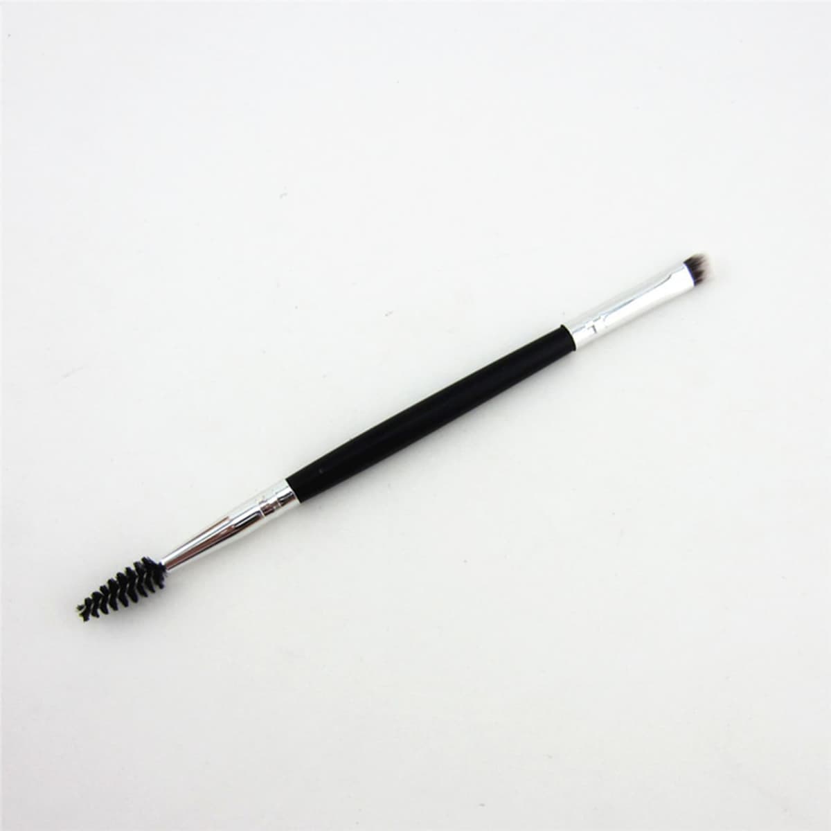 A double-headed eyebrow brush with a black handle, featuring a spoolie brush on one end and a flat brush on the other.