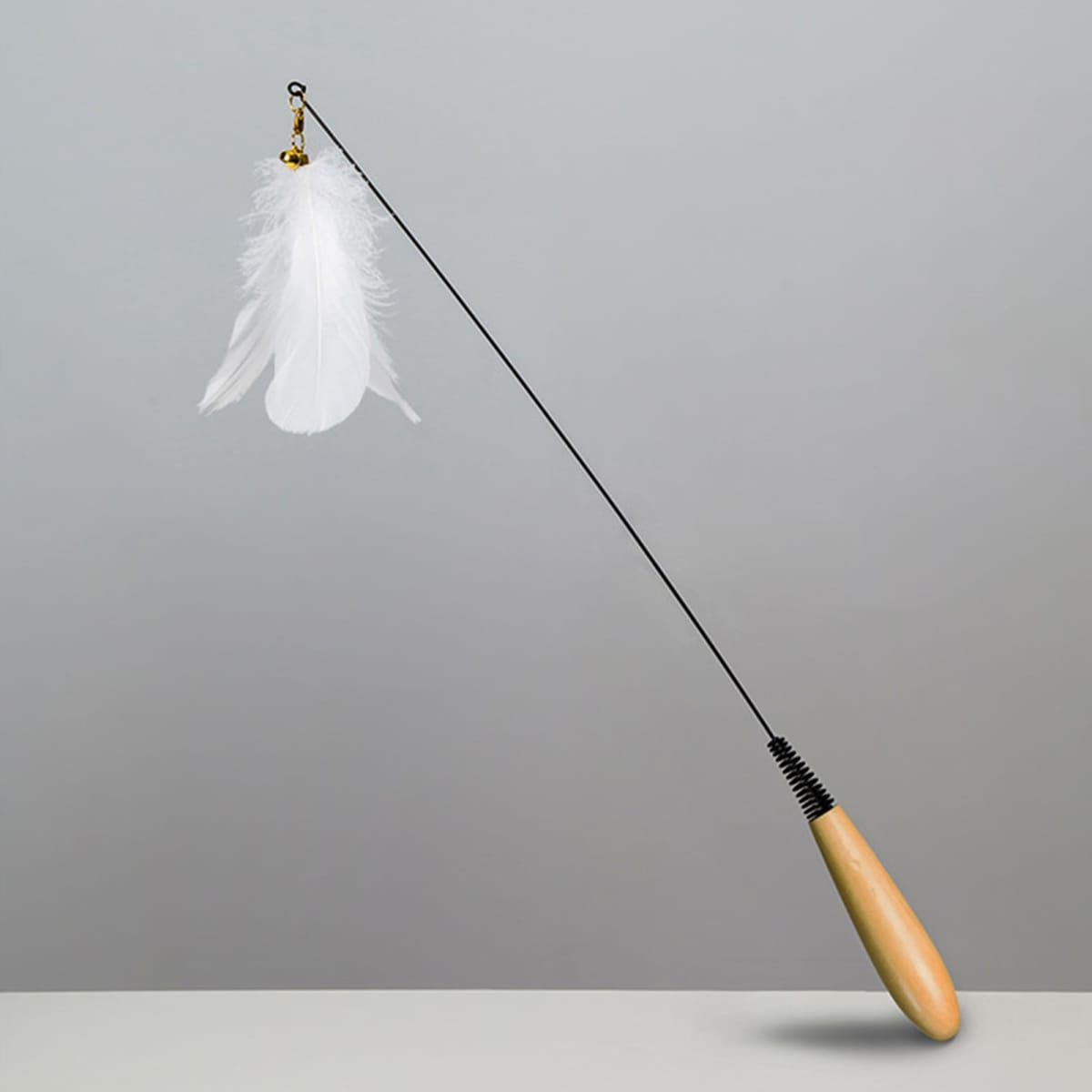 A toy wand with a wooden handle and a long string attached to a white feather.