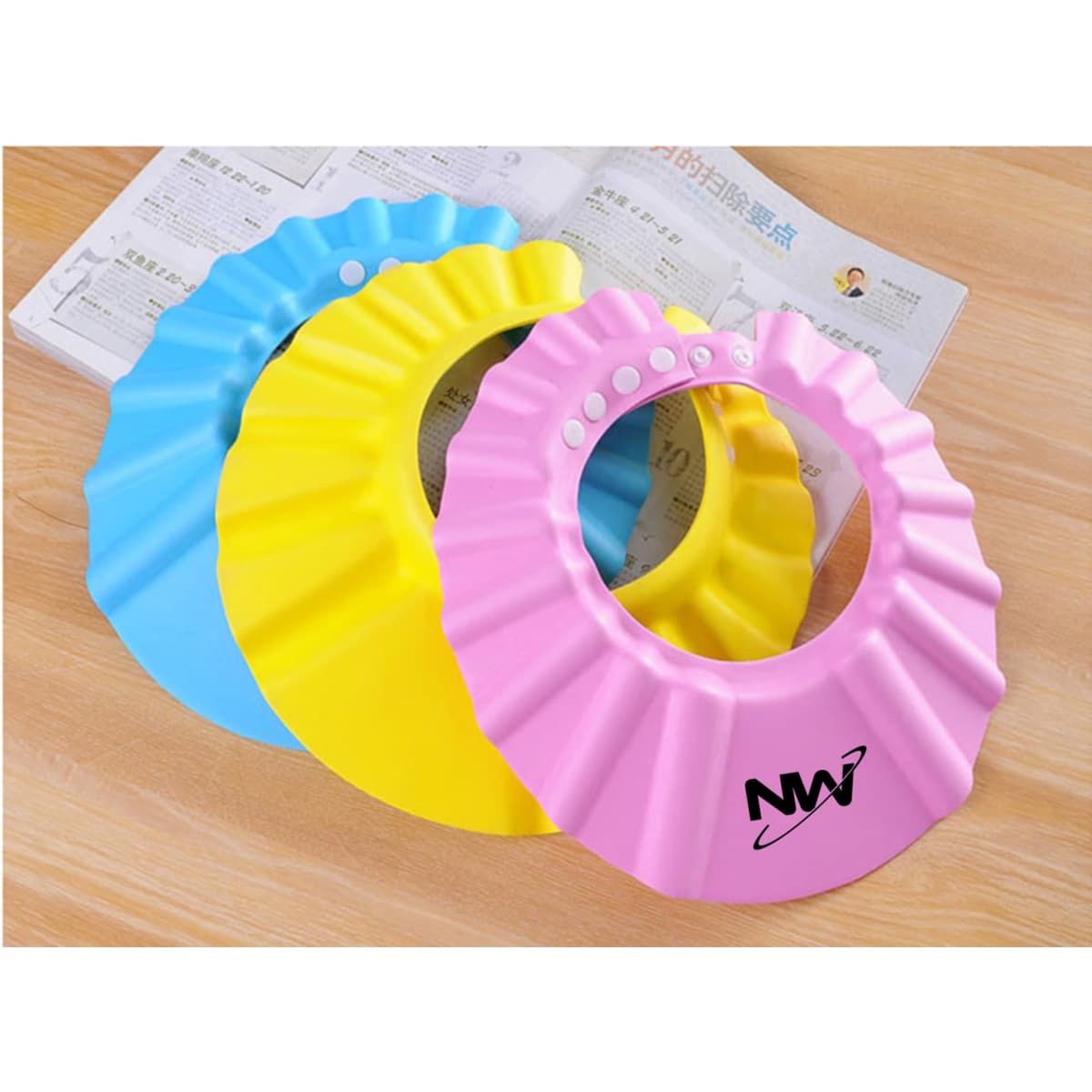 A set of three baby shower caps in blue, yellow, and pink, each with a ruffled design and one featuring a logo.