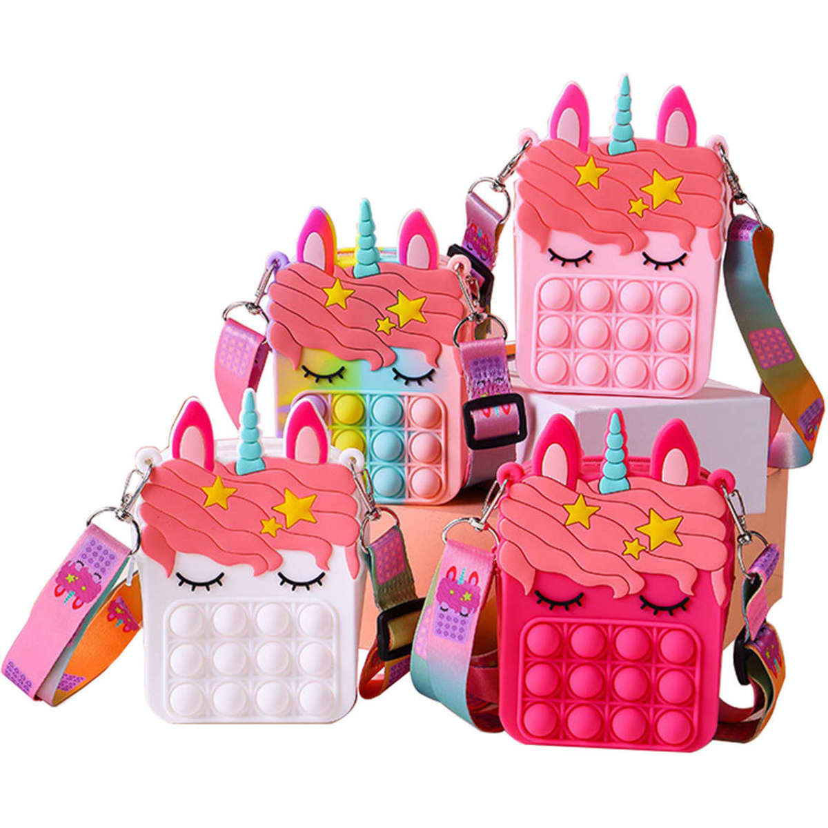 Four unicorn-shaped bags in pink, white, and multicolour with pop bubble features and adjustable straps.
