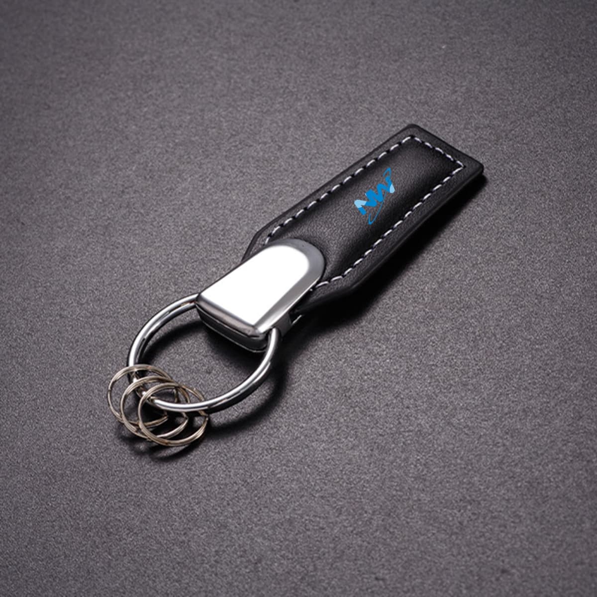 A black leather key chain with a silver keyring and a small logo on the surface.