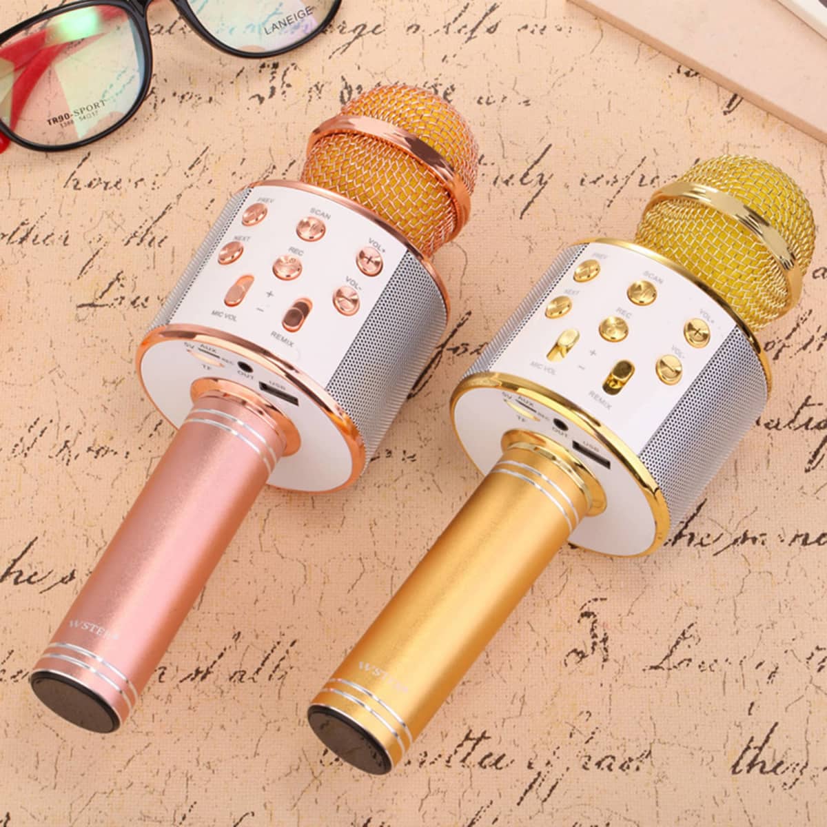 Two multifunctional microphones in gold and rose gold, featuring buttons and a mesh grille atop a sleek design.