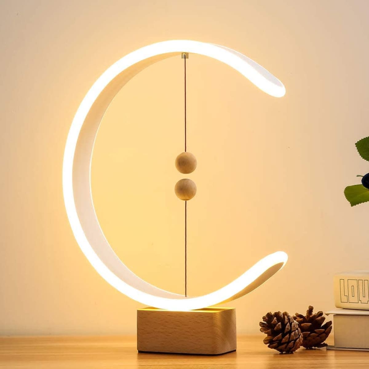 A modern balance lamp in a circular design with glowing white light, featuring wooden accents and a wooden base.