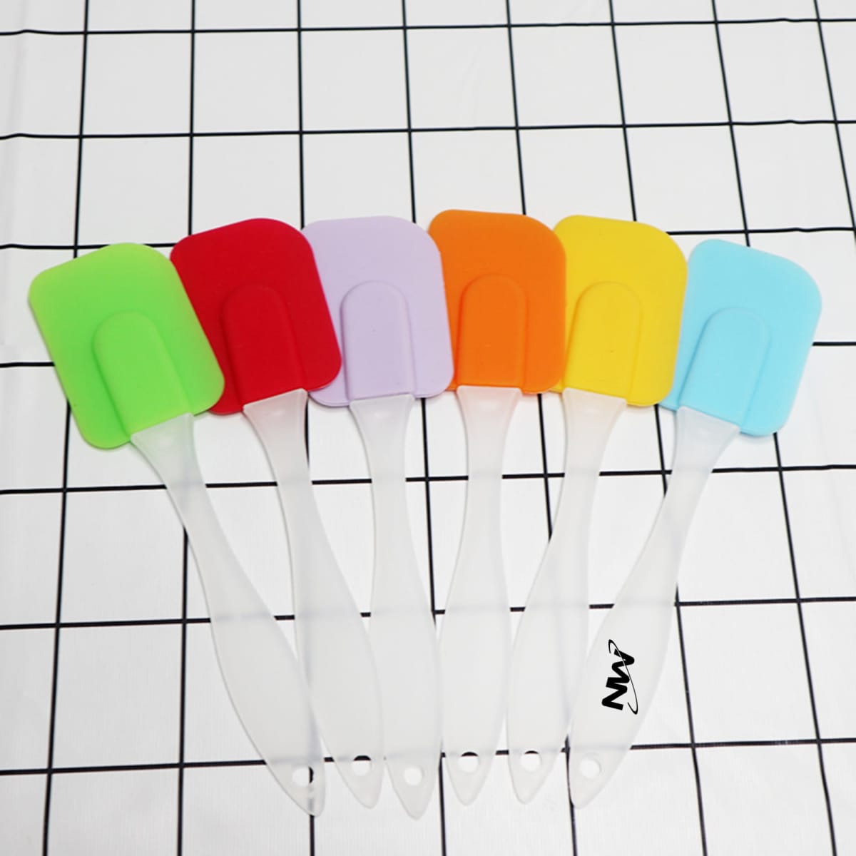 A set of six cream spatulas in vibrant colours: green, red, purple, orange, yellow, and blue, with clear handles.