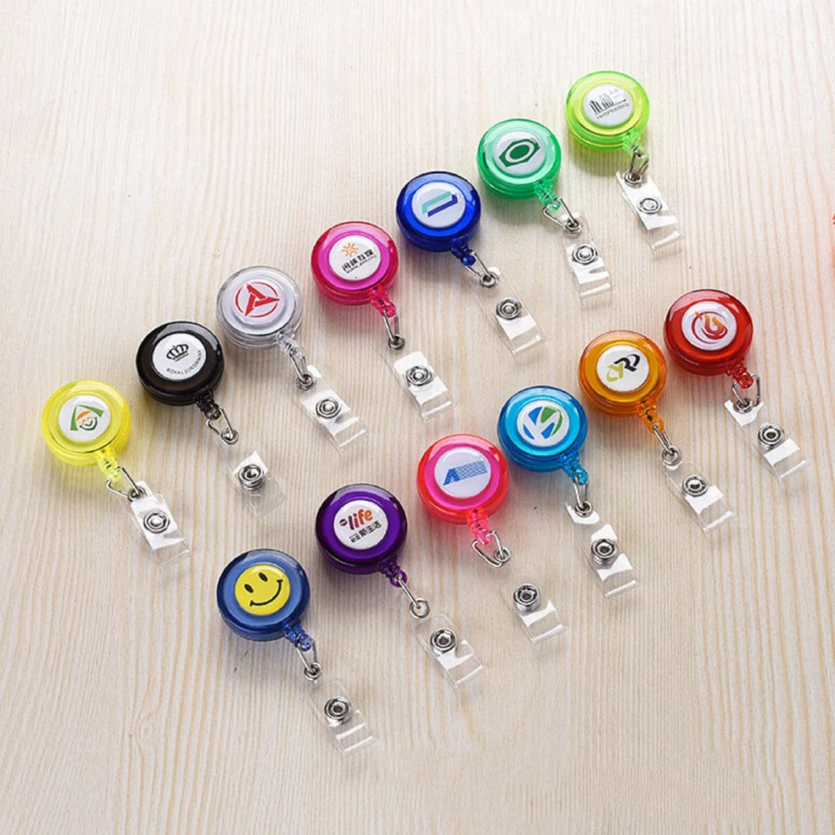 A collection of colourful retractable badge holders in various designs, including yellow, red, blue, green, and purple.