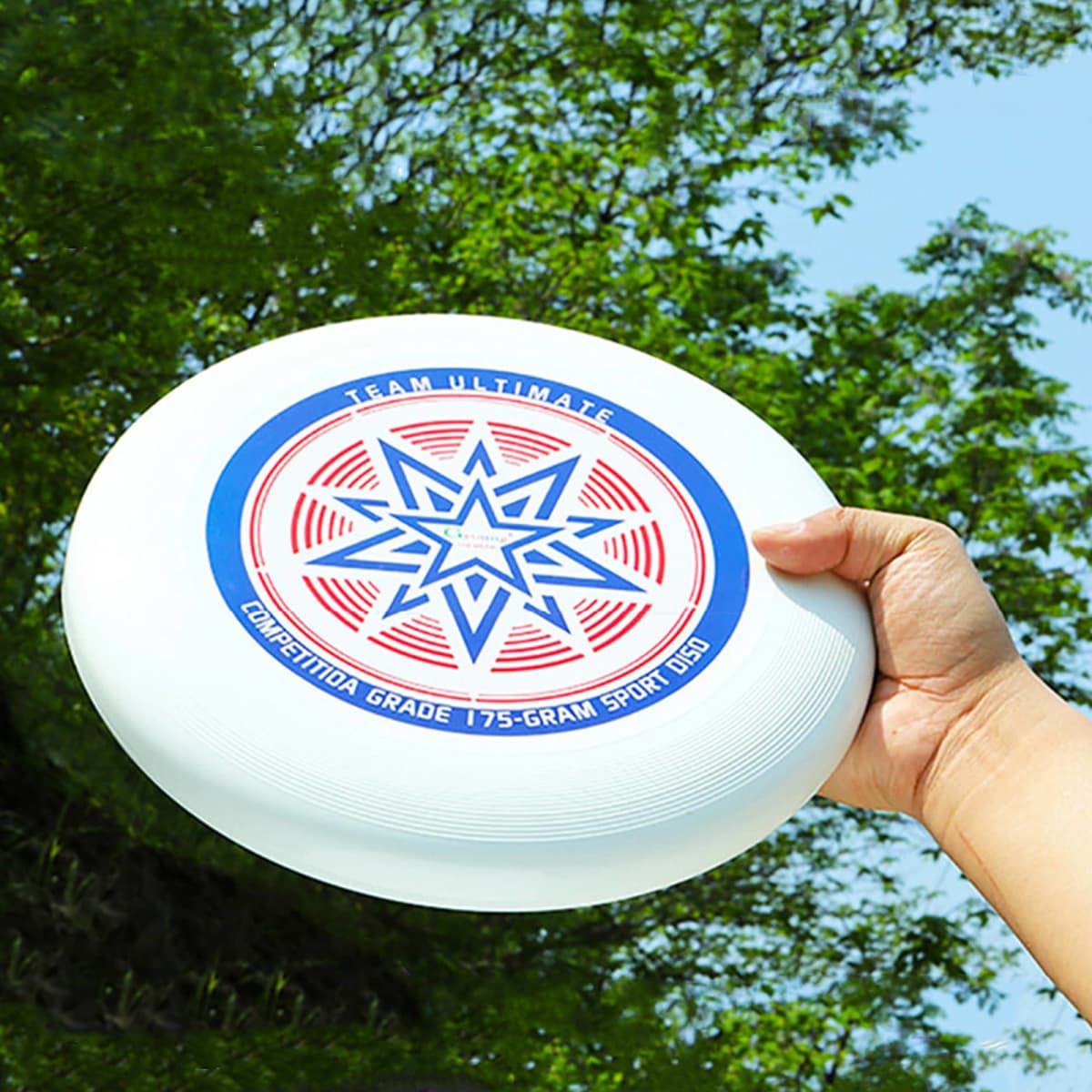A white Ultimate Disc Frisbee held in a hand, featuring a colourful star design and a logo.